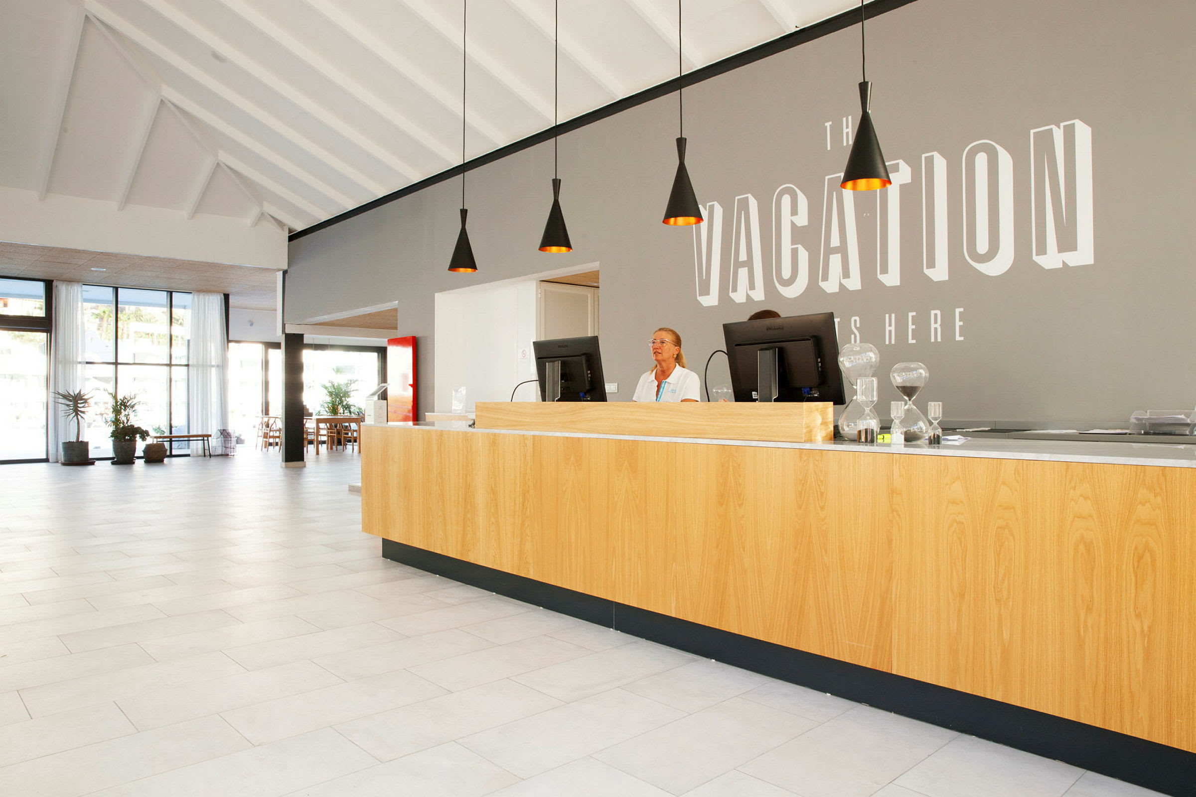 Reception med trädisk och datorer i ett ljust hotellområde. (AI-genererad text)
