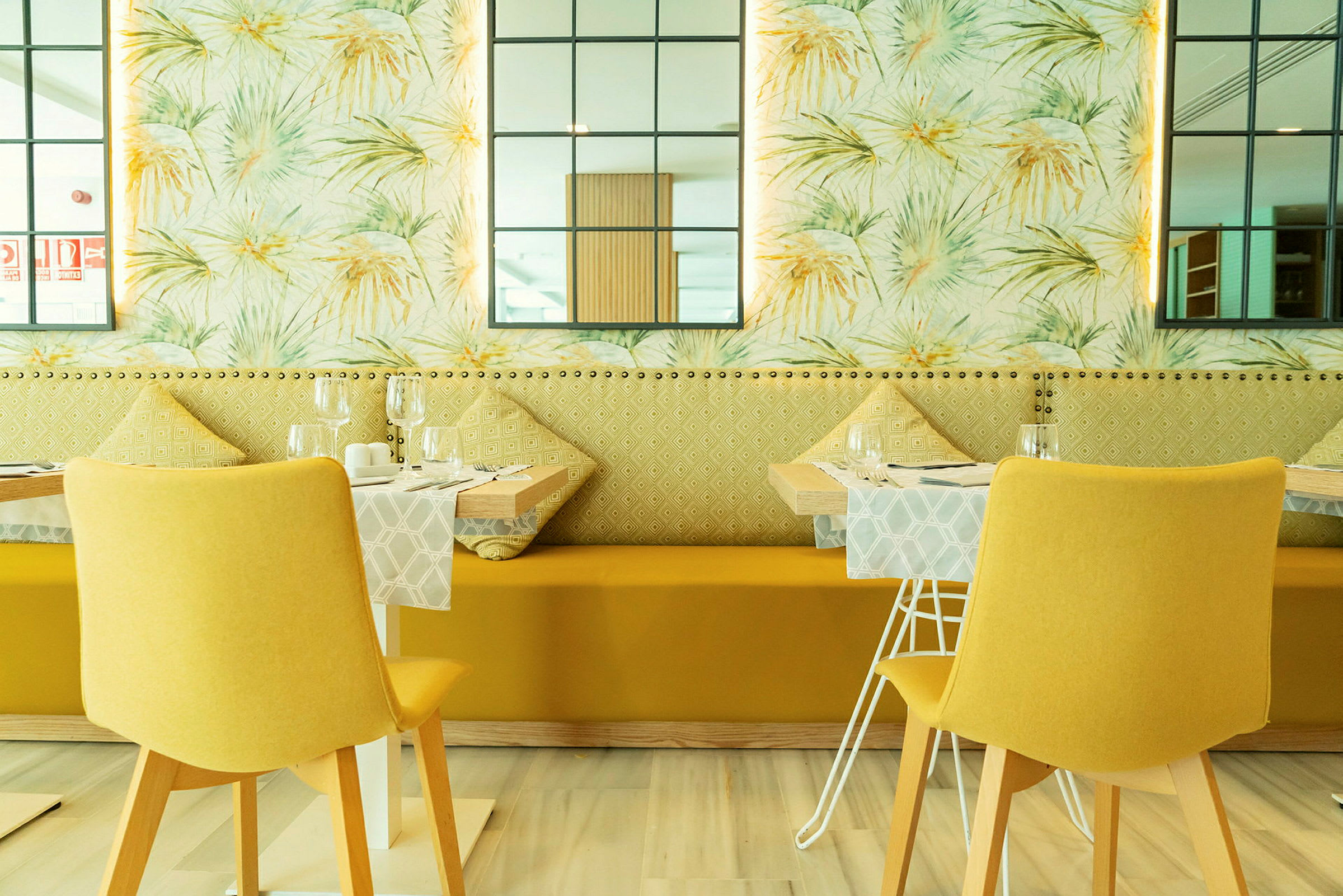Restaurang med modern inredning, gula stolar och dekorativa väggdetaljer. (AI-genererad text)