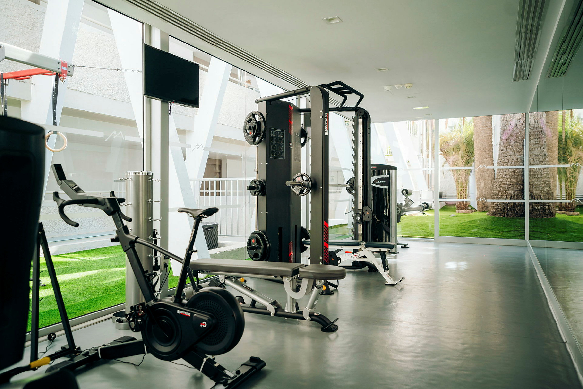Gym med träningsutrustning och fönster med utsikt. (AI-genererad text)