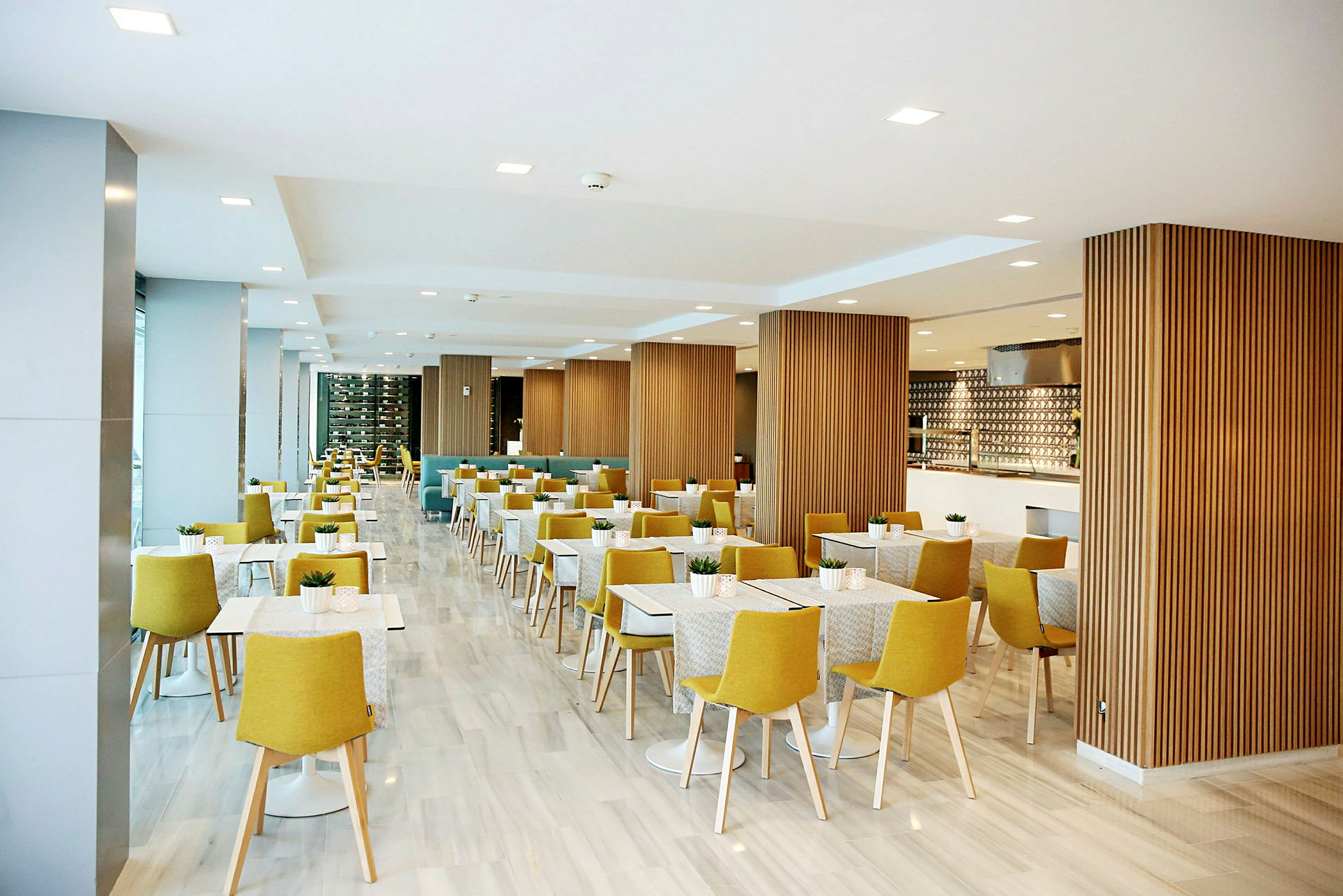 Restaurang med ljus inredning, gula stolar och vita bord. (AI-genererad text)