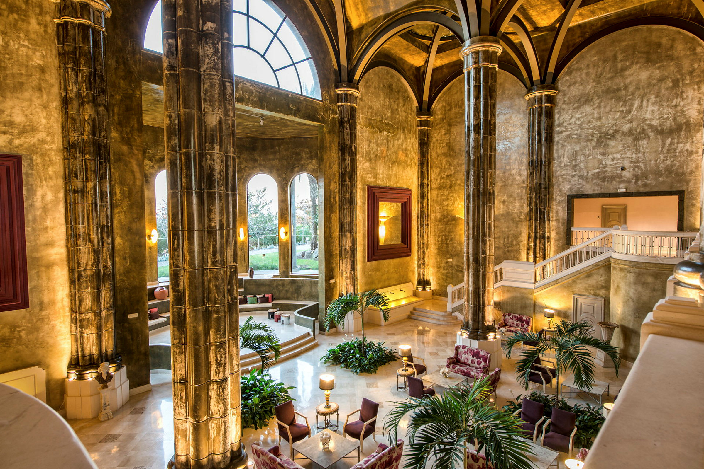 Ett elegant hotellobby med höga välvda tak och stora pelare. Fönster släpper in naturligt ljus. (AI-genererad text)