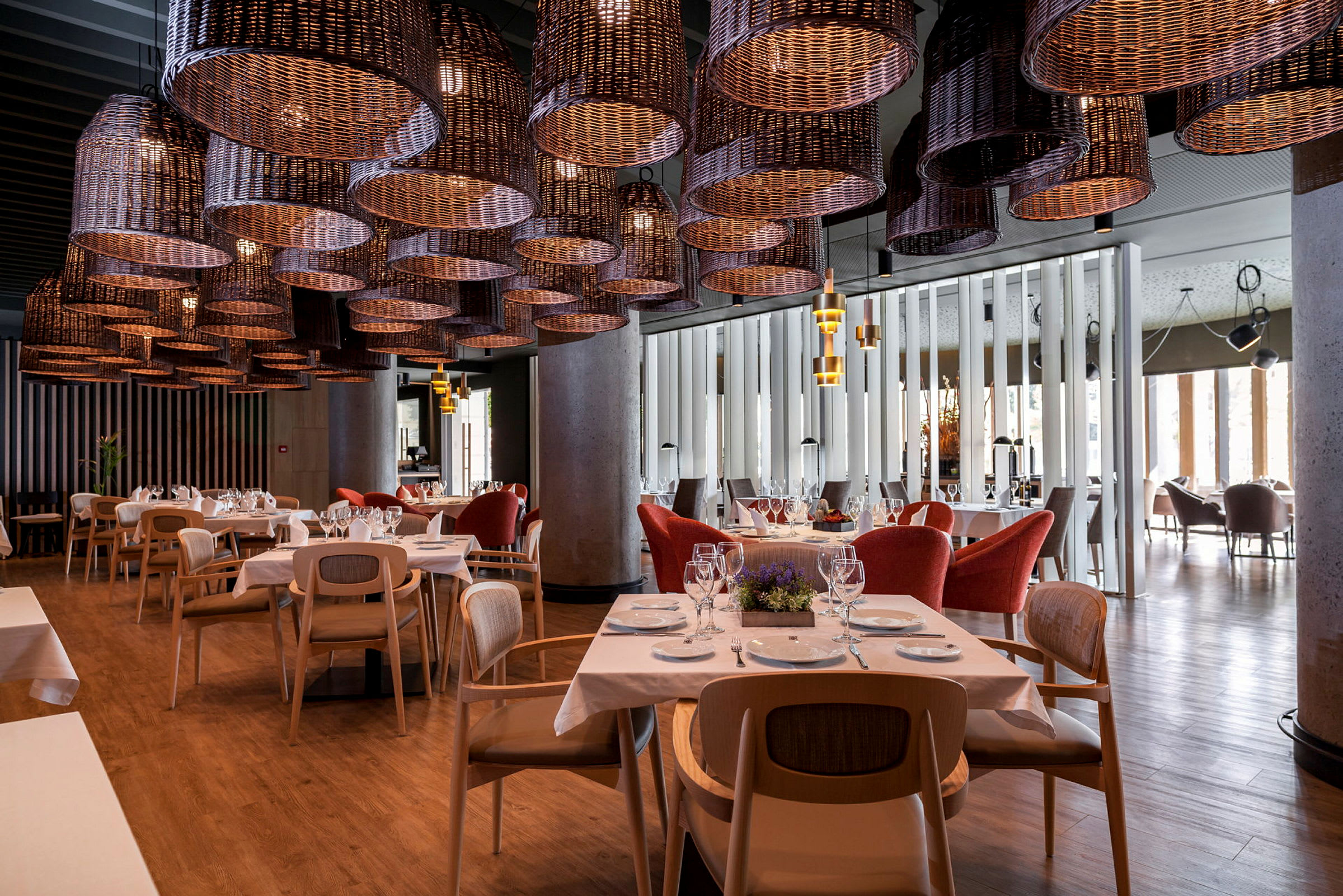 Restaurang med dukade bord, moderna trästolar och stora korglampor i taket. (AI-genererad text)