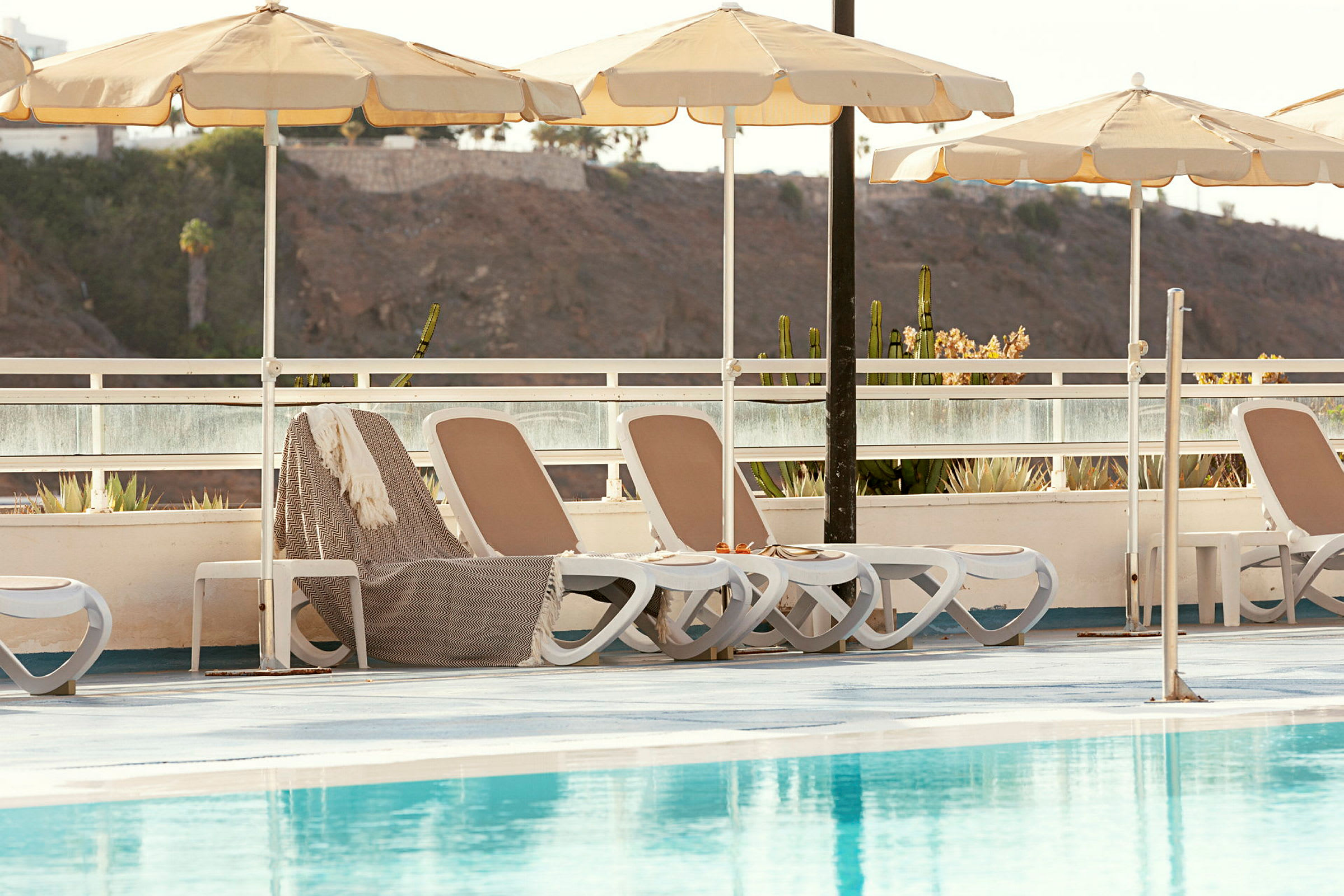 Solstolar med parasoller vid en pool. (AI-genererad text)