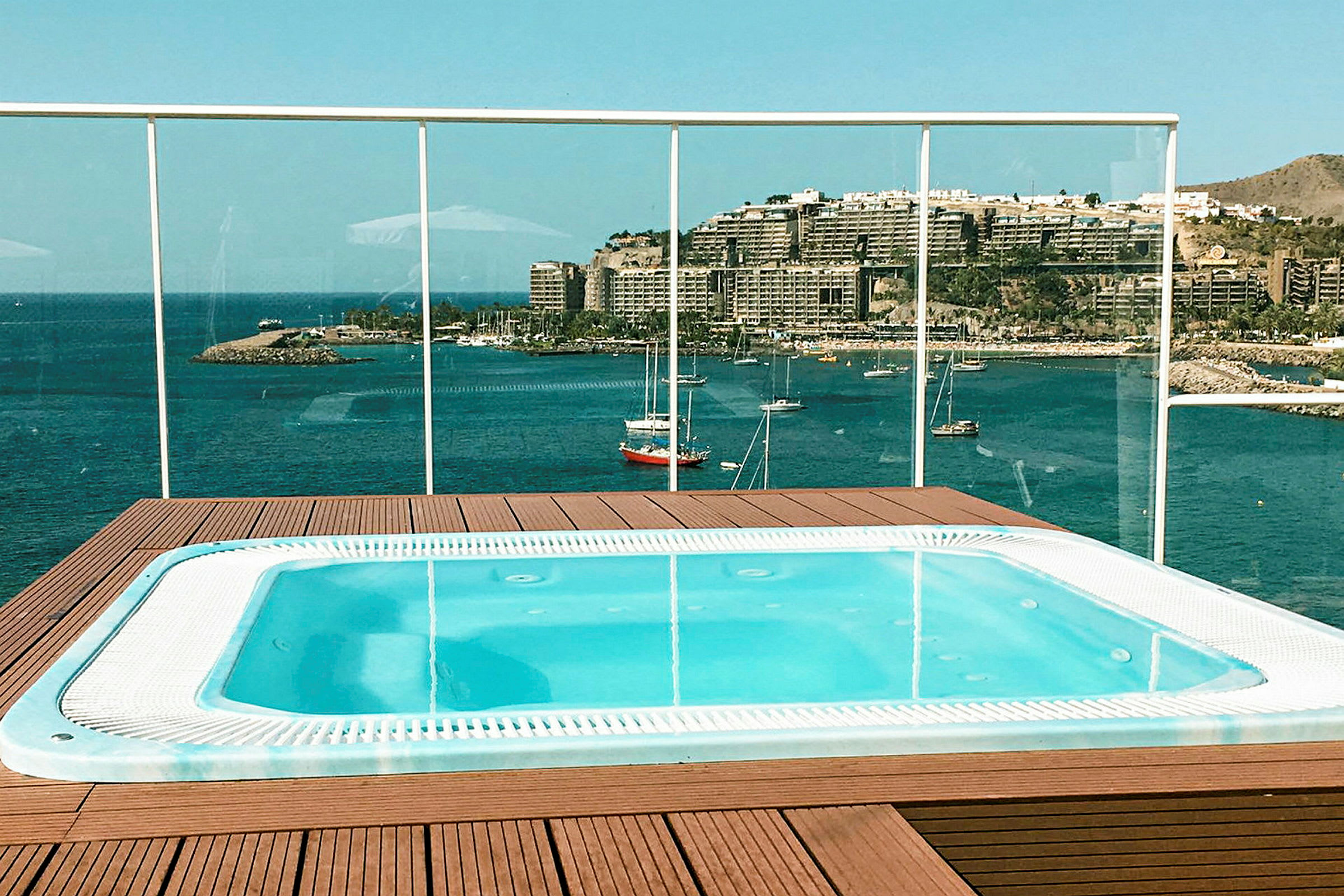 Bild av en jacuzzi med panoramautsikt över en hamn och byggnader vid en kust. (AI-genererad text)