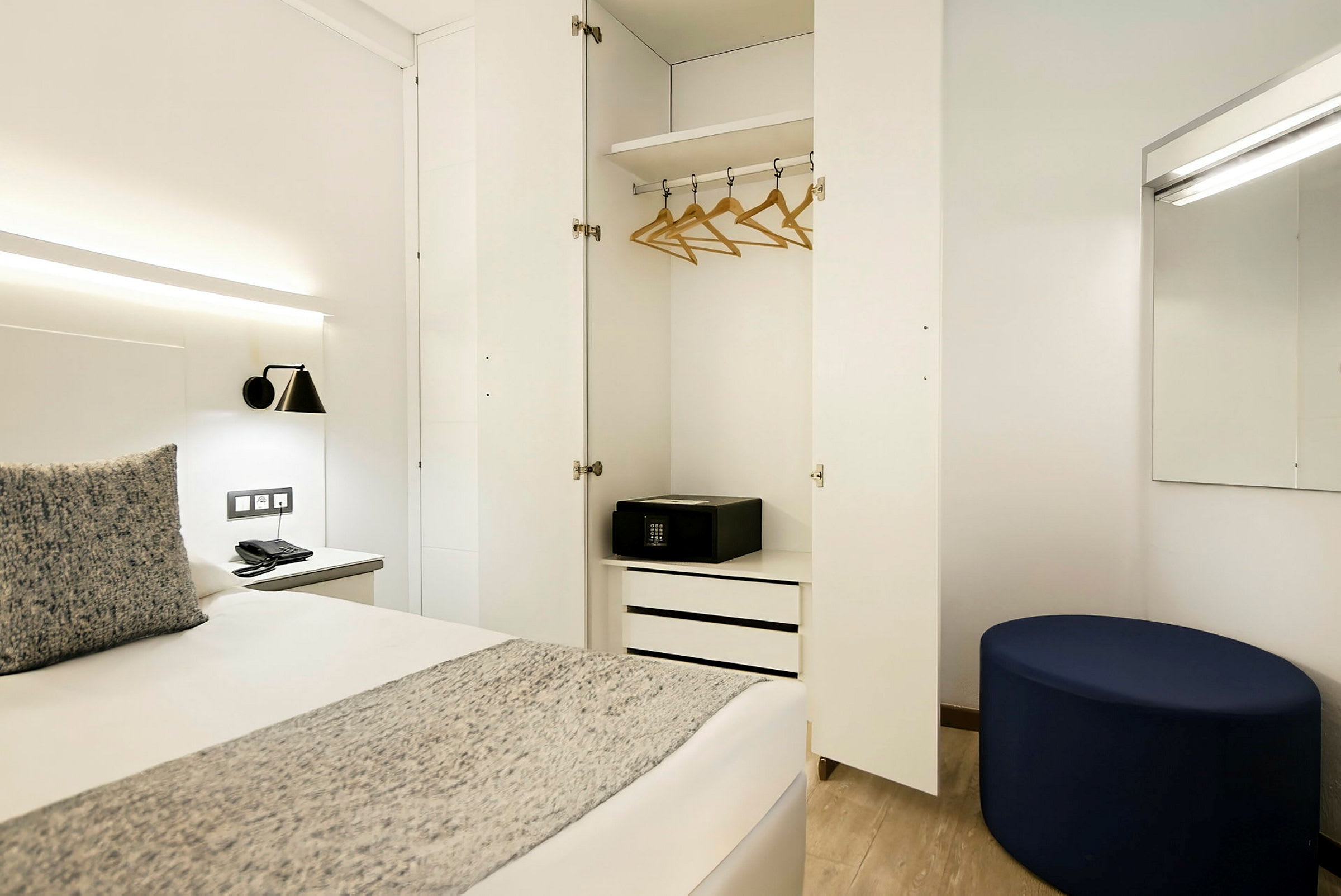 En hotellrum med öppen garderob, säng, och spegel. (AI-genererad text)