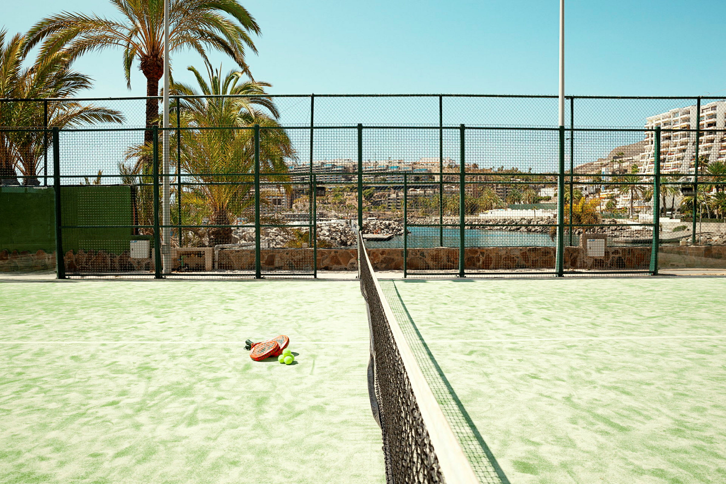 En padelplan med ett racket och bollar på marken. (AI-genererad text)