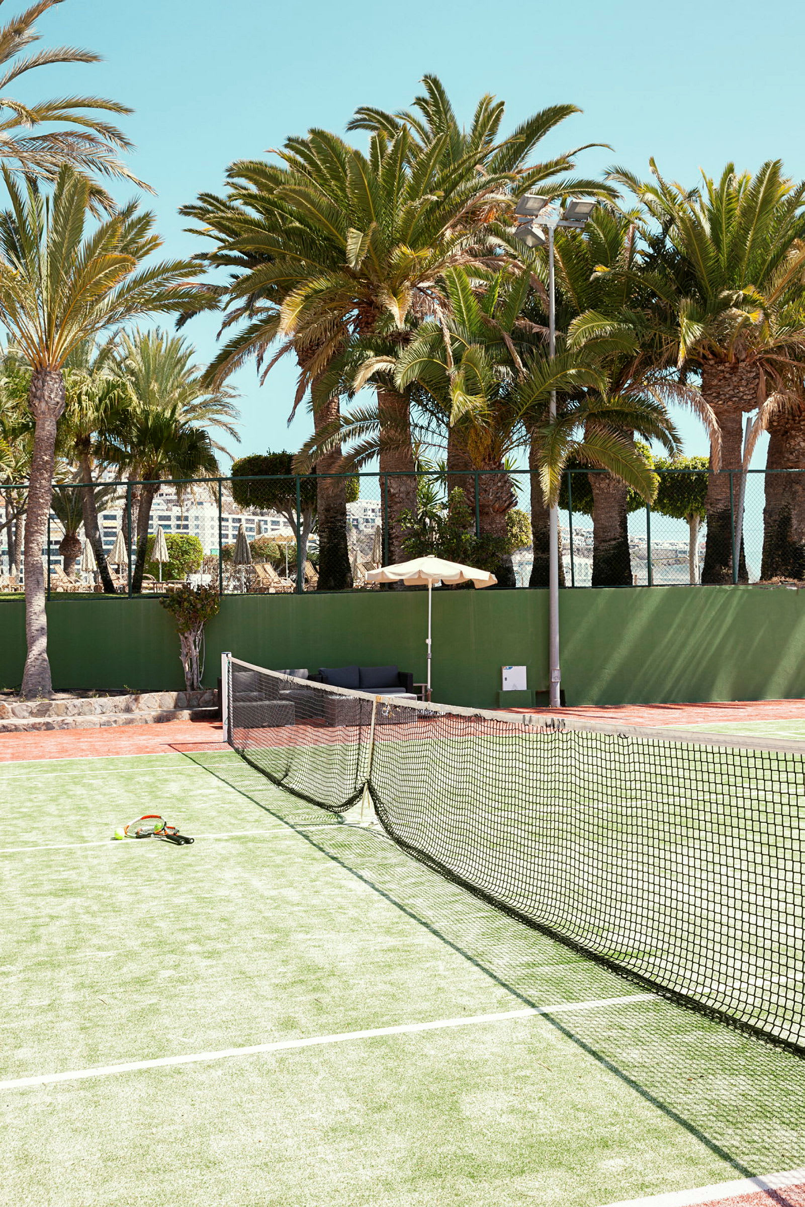En tennisbana med nät och racketar, omgiven av palmer. (AI-genererad text)