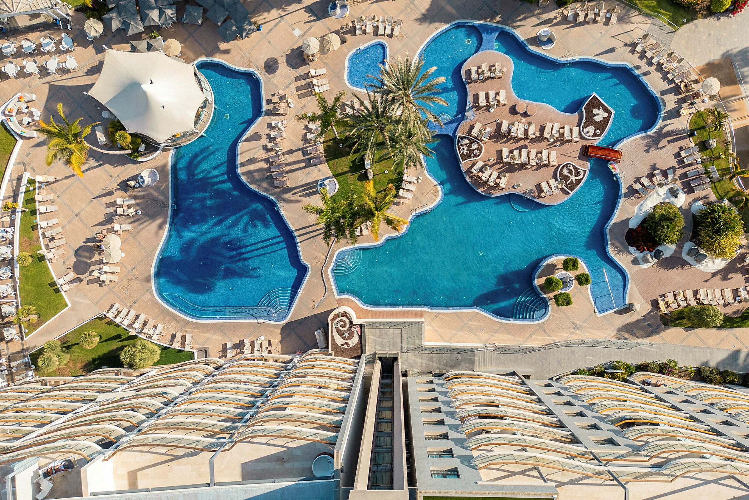 En översiktsbild av en utomhuspool med solstolar och parasoller vid ett hotell. (AI-genererad text)