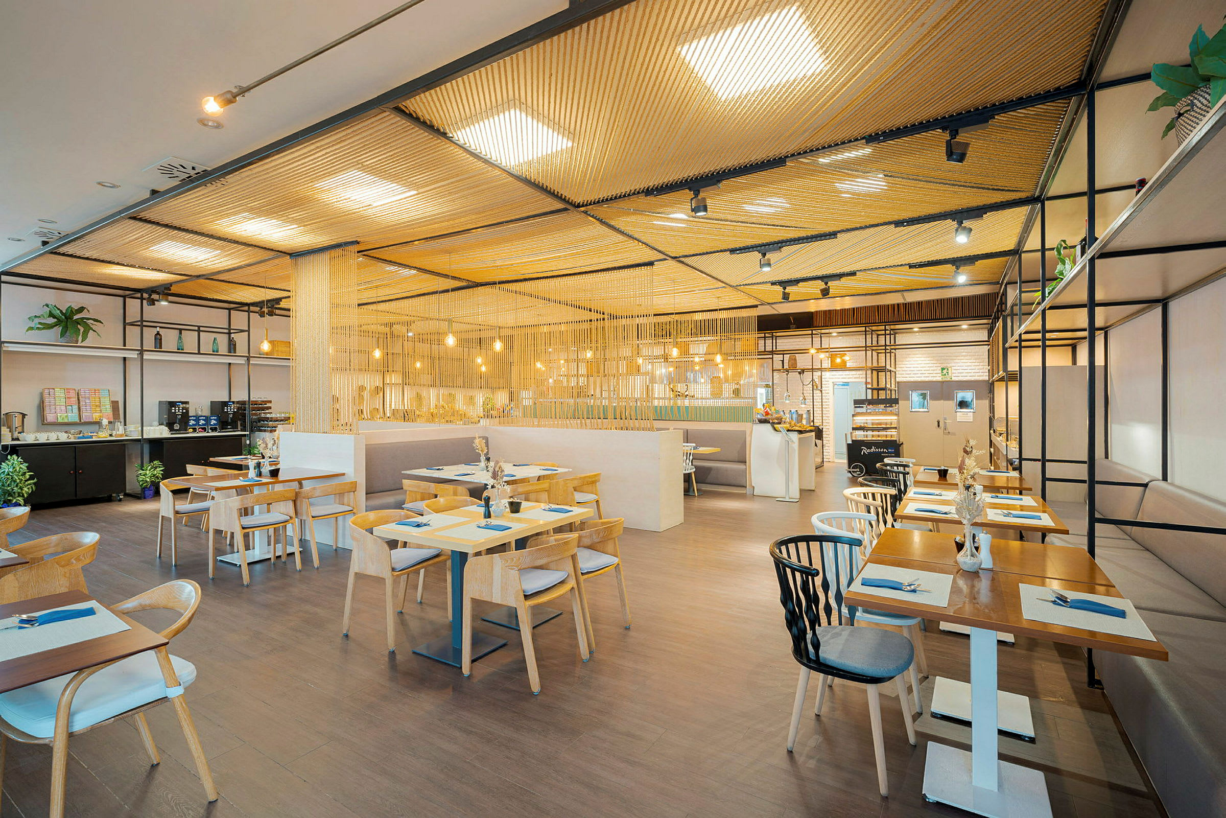 En modern restaurang med träbord och stolar, upplyst av hängande lampor. (AI-genererad text)