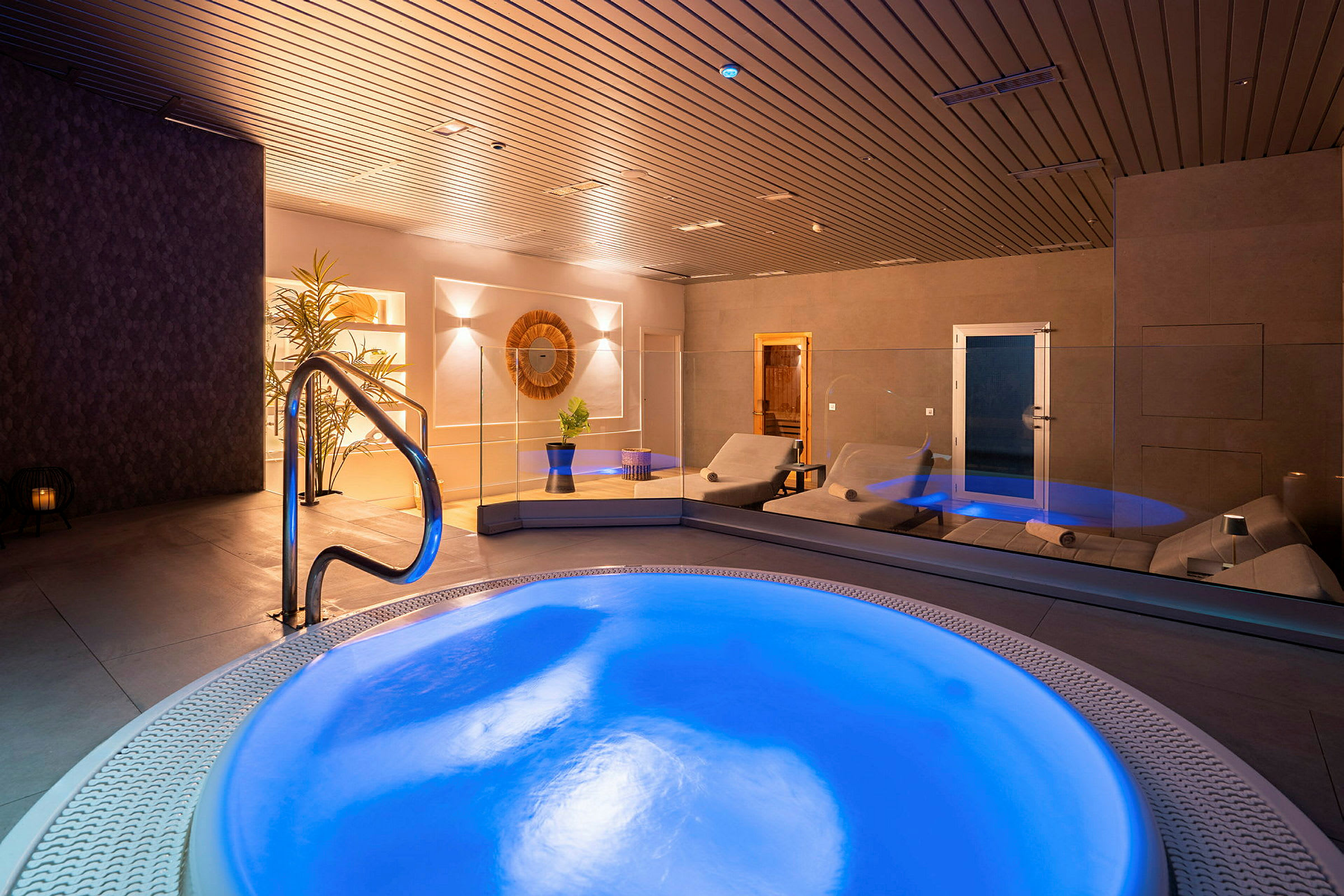 Interiör av ett spa med en belyst jacuzzi och vilstolar. (AI-genererad text)
