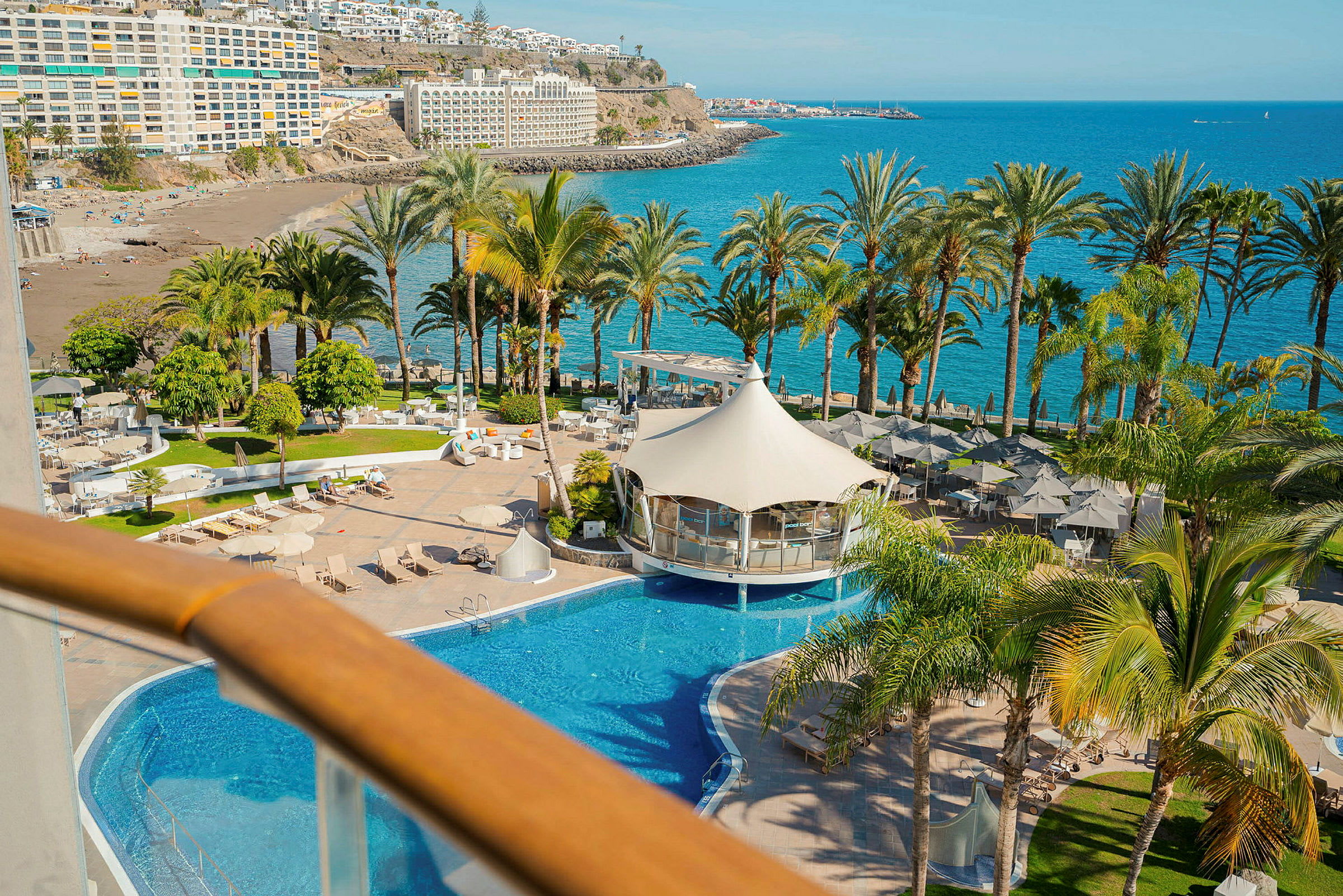 Bild av en resort med pool, solstolar, palmer och hav i bakgrunden. (AI-genererad text)