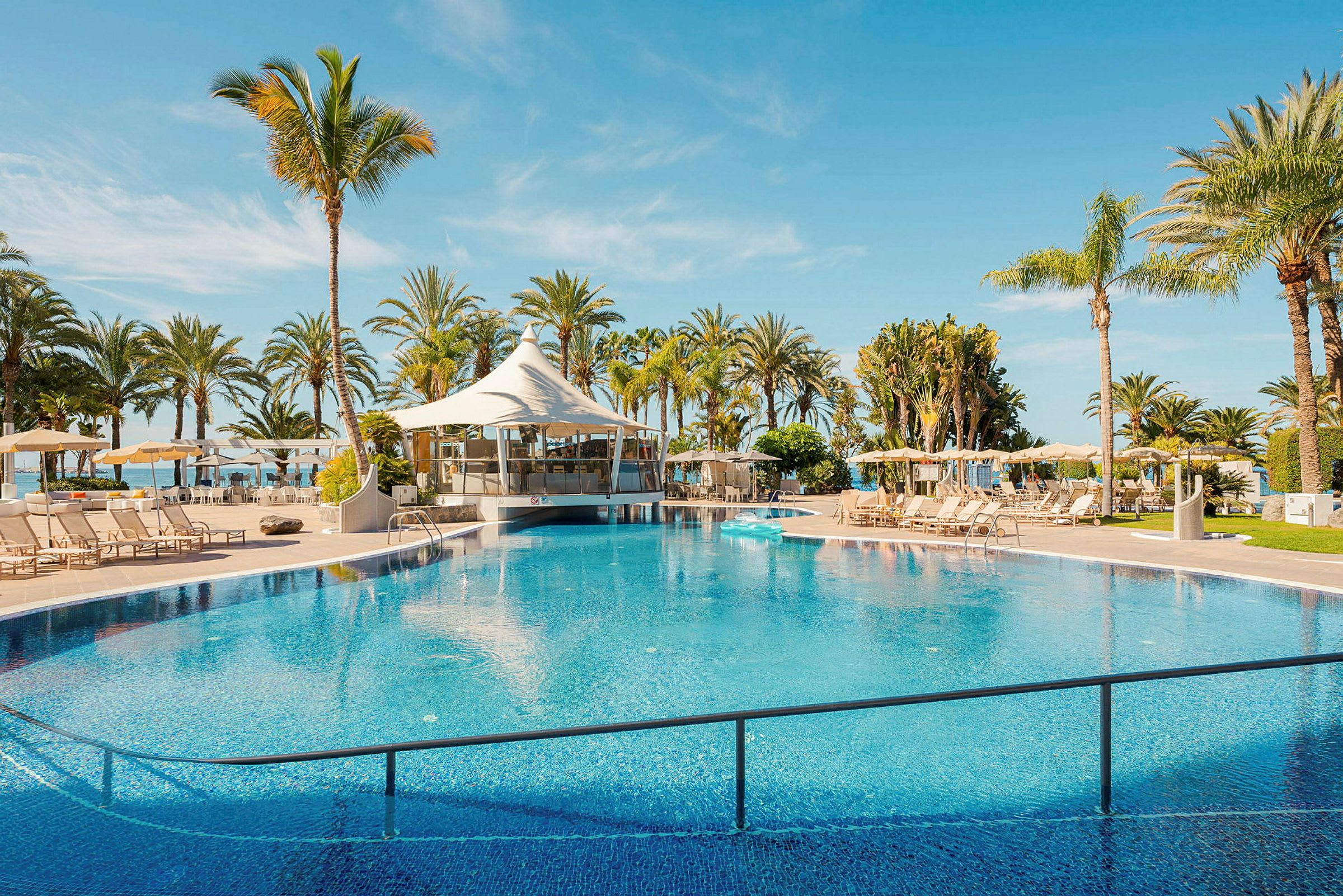 Pool med sittmöbler och palmträd. (AI-genererad text)