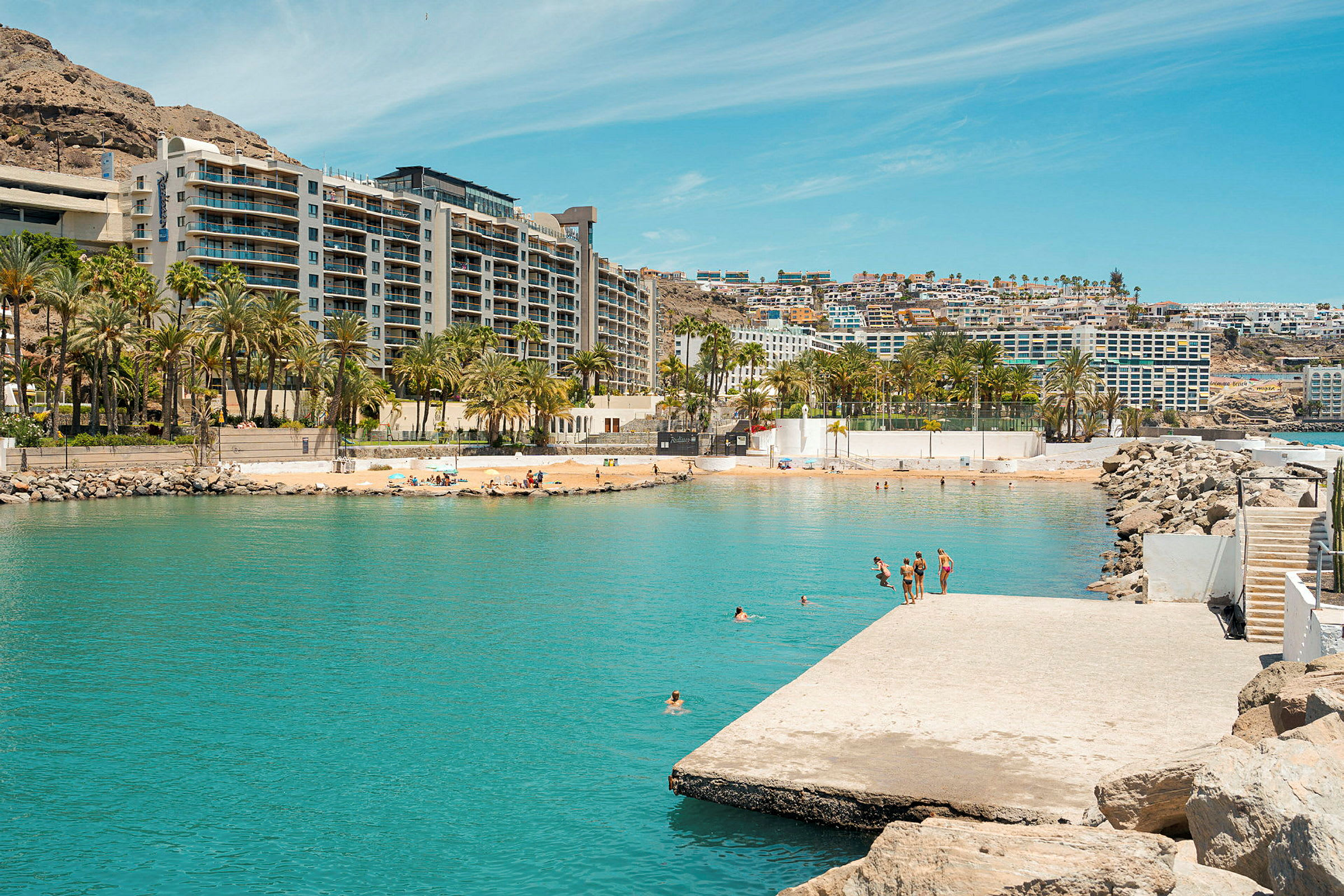 En strand med turkost vatten och hotell i bakgrunden. (AI-genererad text)