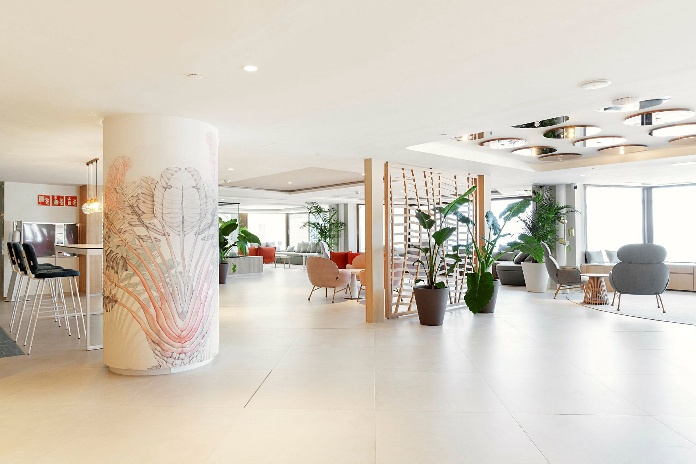 En rymlig och ljust inredd hotellobby med flera sittmöbler och gröna växter. (AI-genererad text)