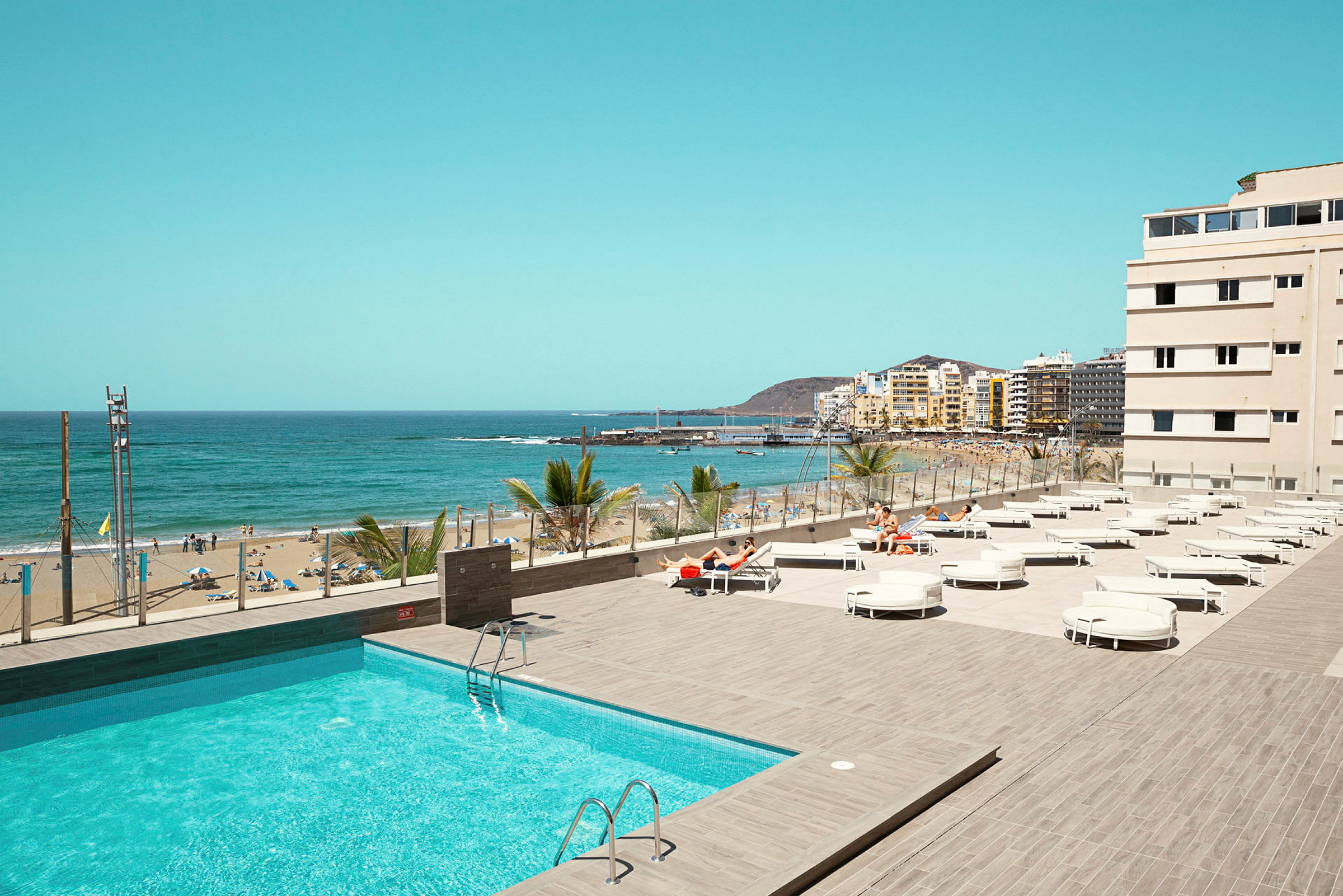 Utsikt över en pool och en strand med hav i bakgrunden. (AI-genererad text)
