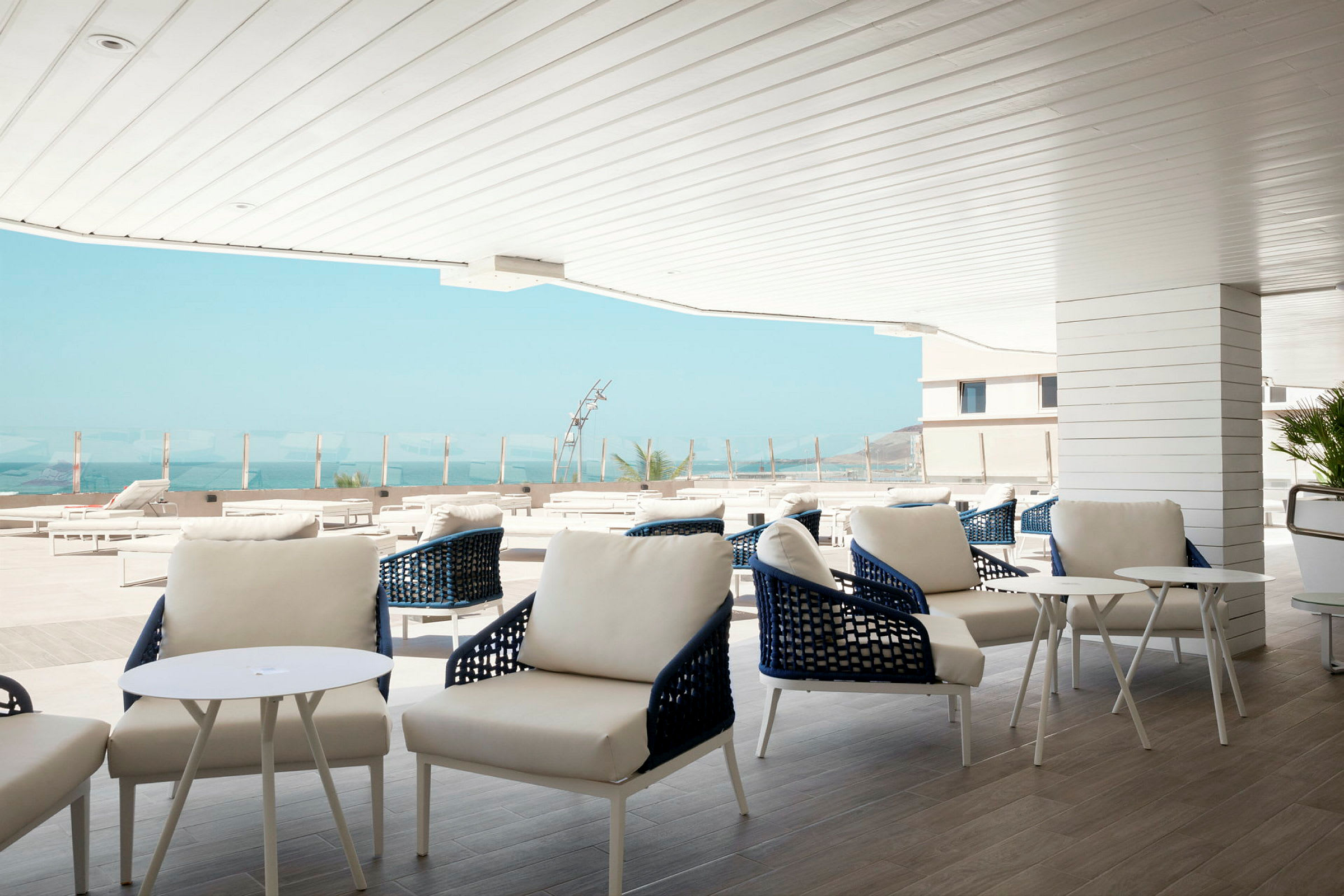 Modern utomhuslounge med vita möbler och utsikt över havet. (AI-genererad text)