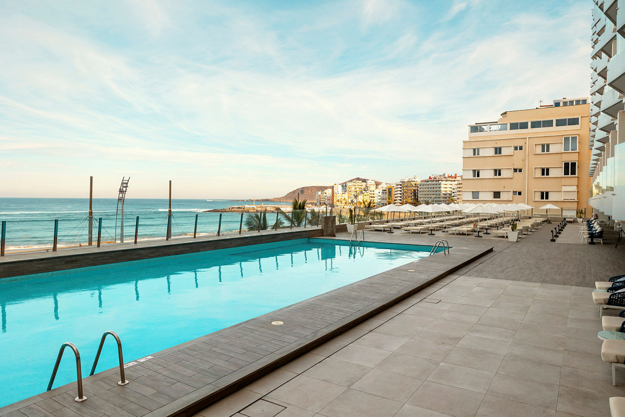 Utomhuspool vid hotellet, med utsikt över stranden och havet. (AI-genererad text)