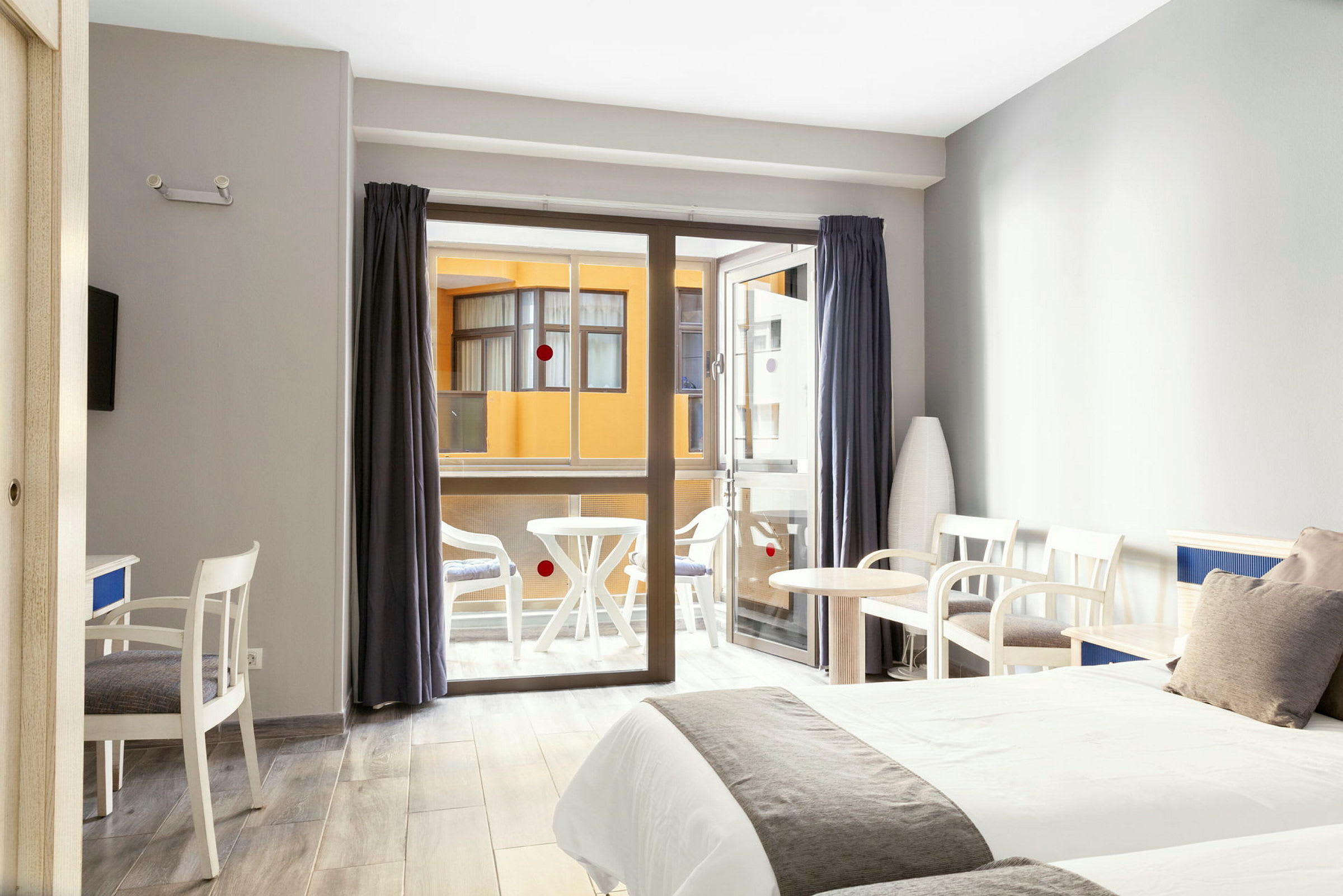 Hotellrum med två sängar, sittmöbler och en balkong i bakgrunden. (AI-genererad text)