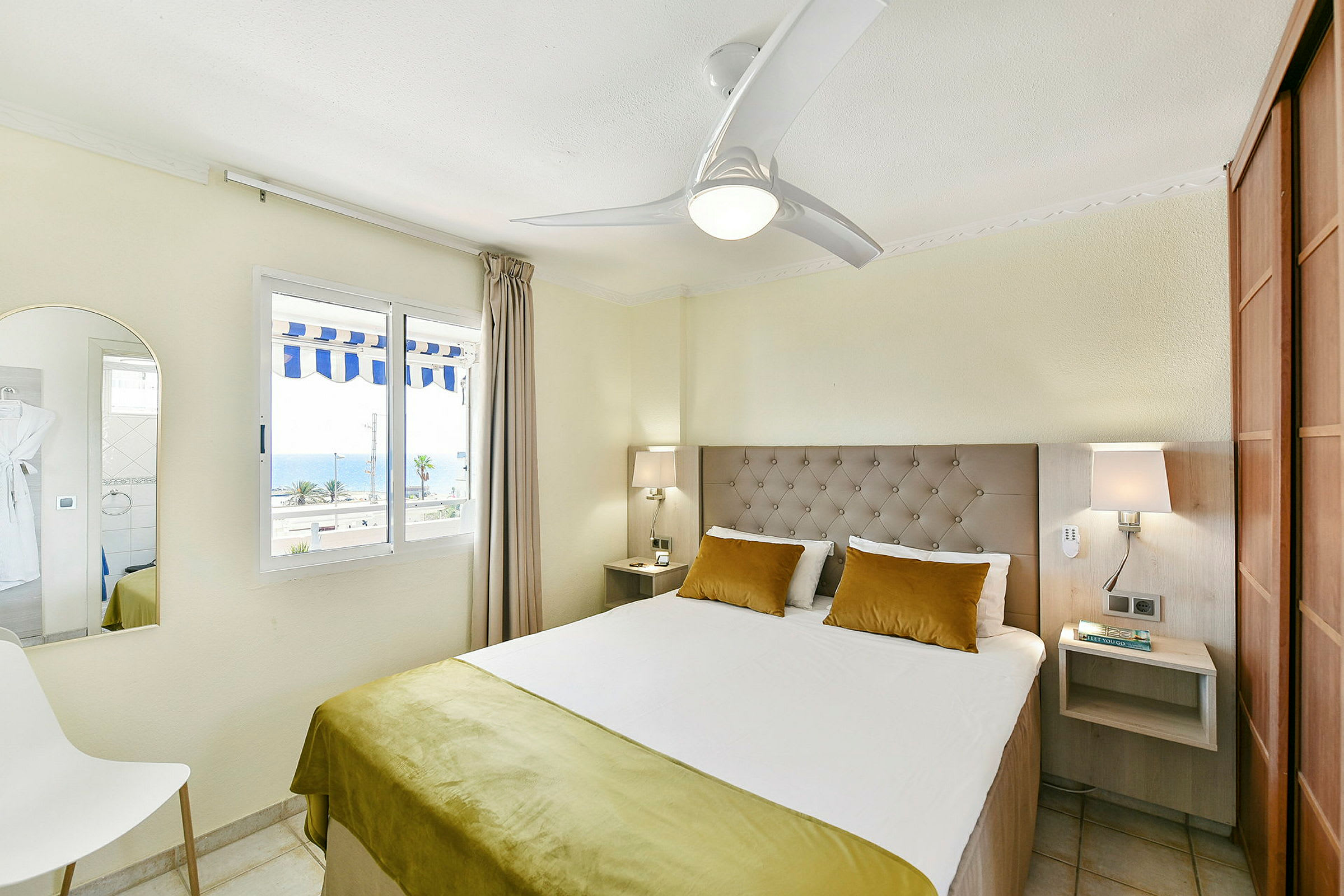 Ett hotellrum med en dubbelsäng och fönster med utsikt över havet. (AI-genererad text)