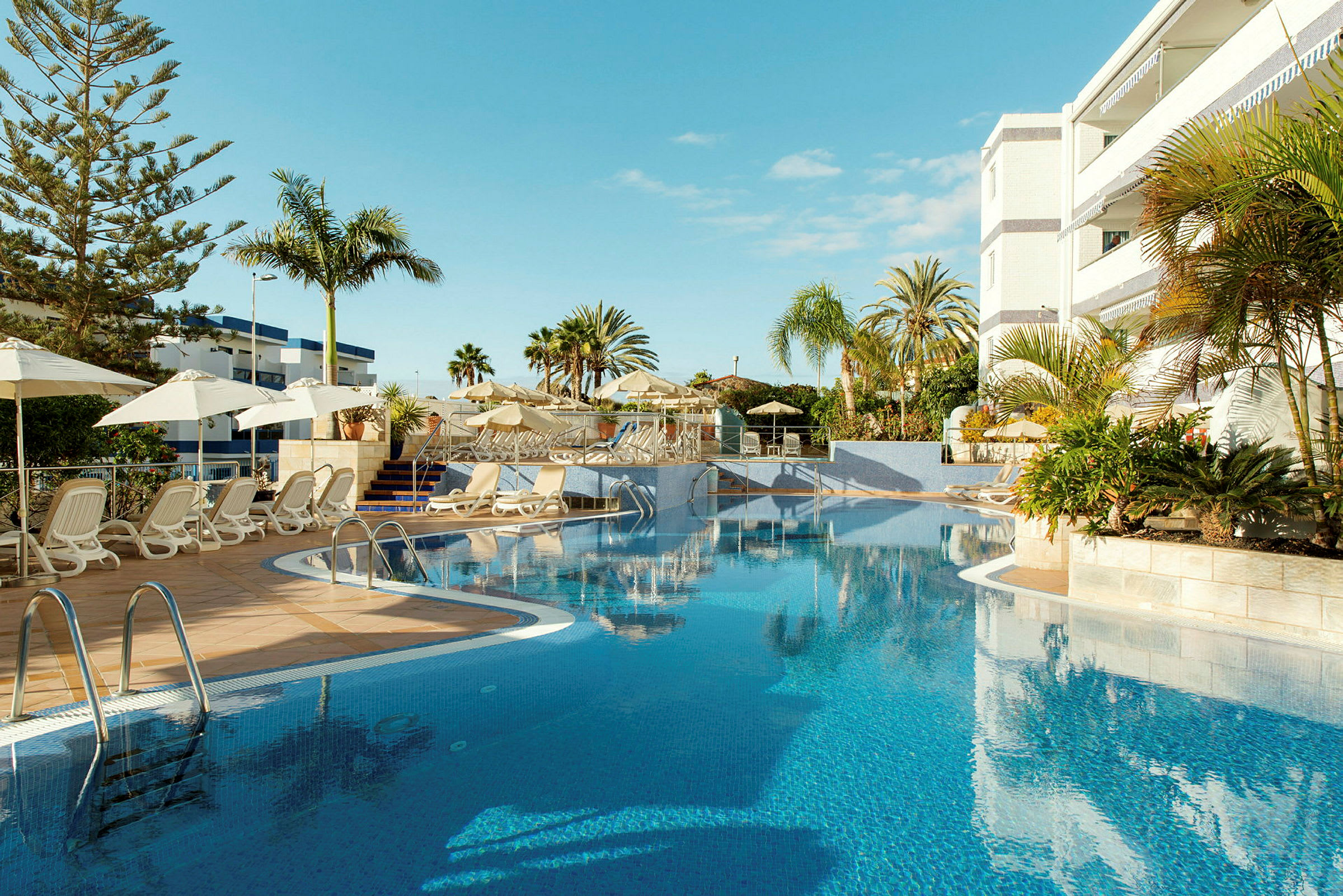 Utomhuspool med solstolar och parasoller vid ett hotell. (AI-genererad text)