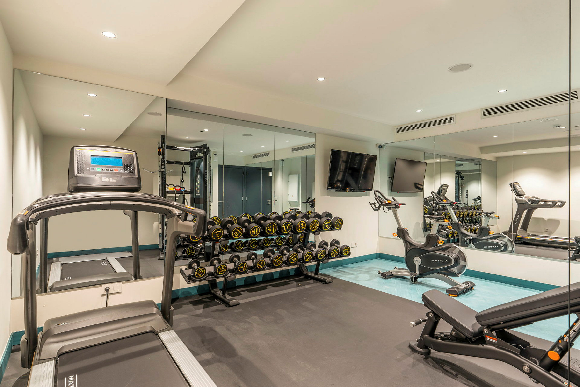 Ett gym med löpband, träningscyklar, bänkpress och viktställ. (AI-genererad text)