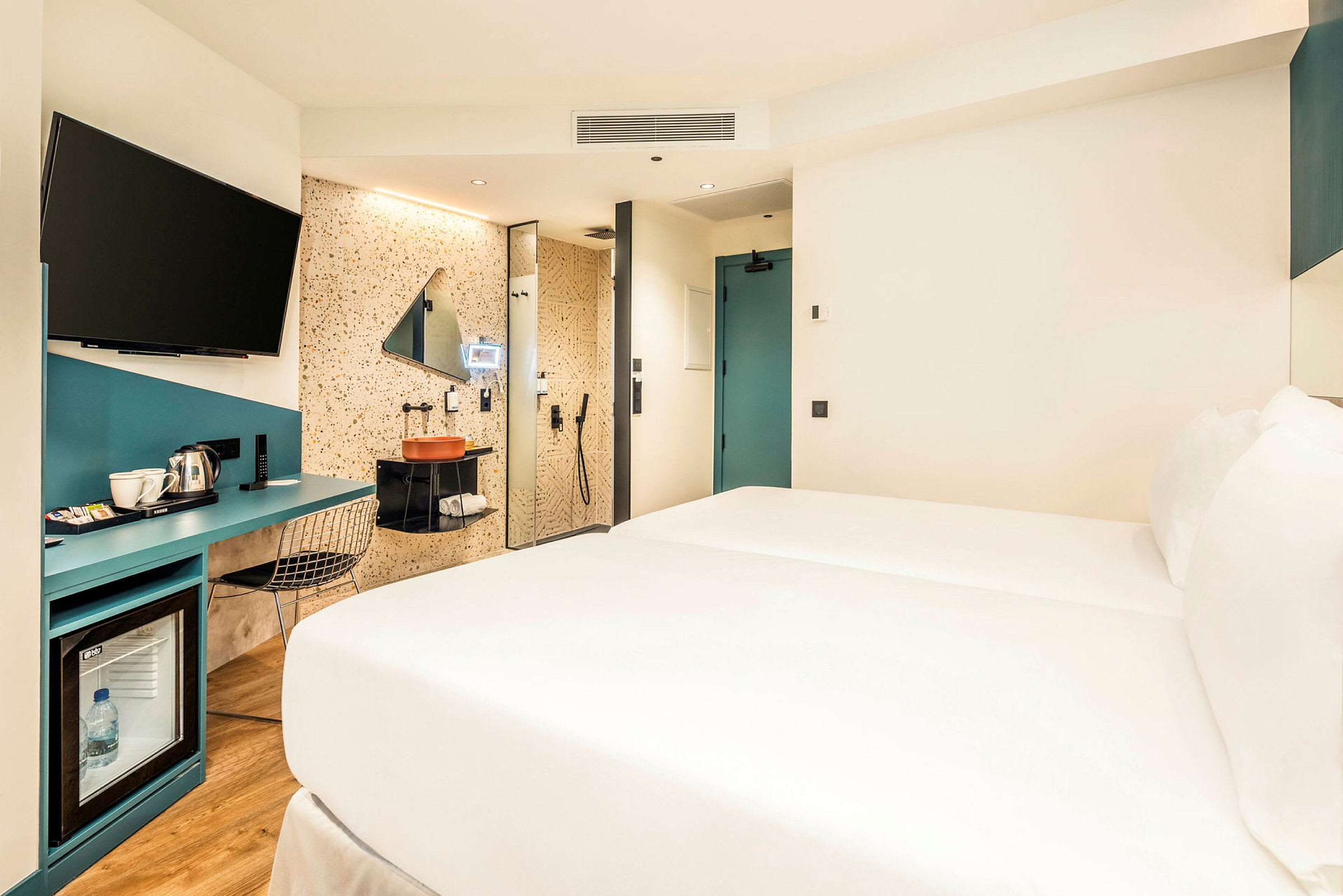 Hotellrum med säng, skrivbord och badrumsområde. (AI-genererad text)