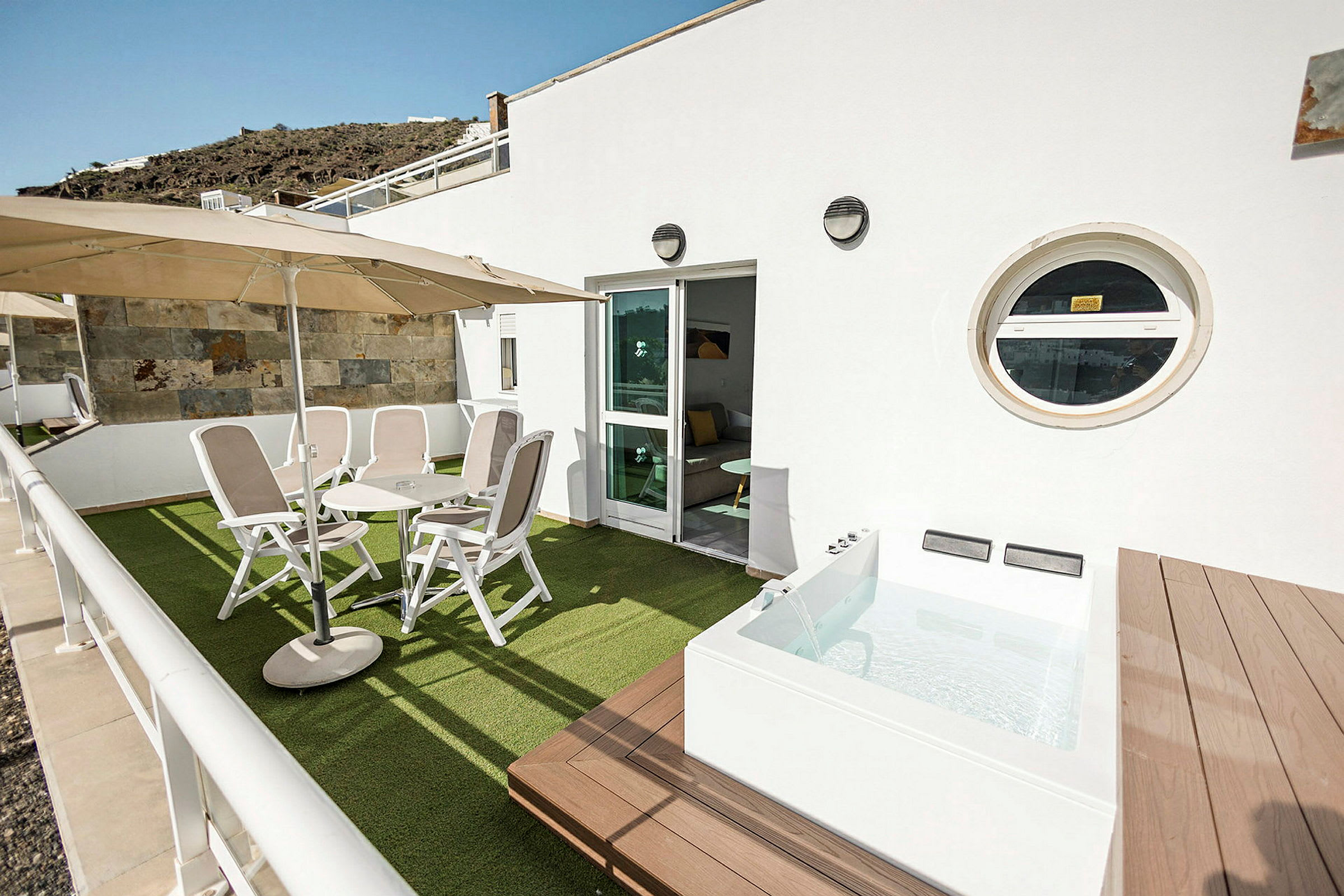 Terrass med stolar, bord och en mindre pool. (AI-genererad text)