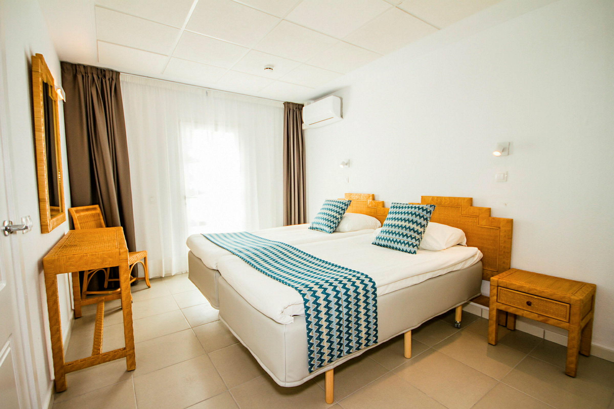Ett hotellrum med två enkelsängar, bambumöbler och vita väggar. (AI-genererad text)