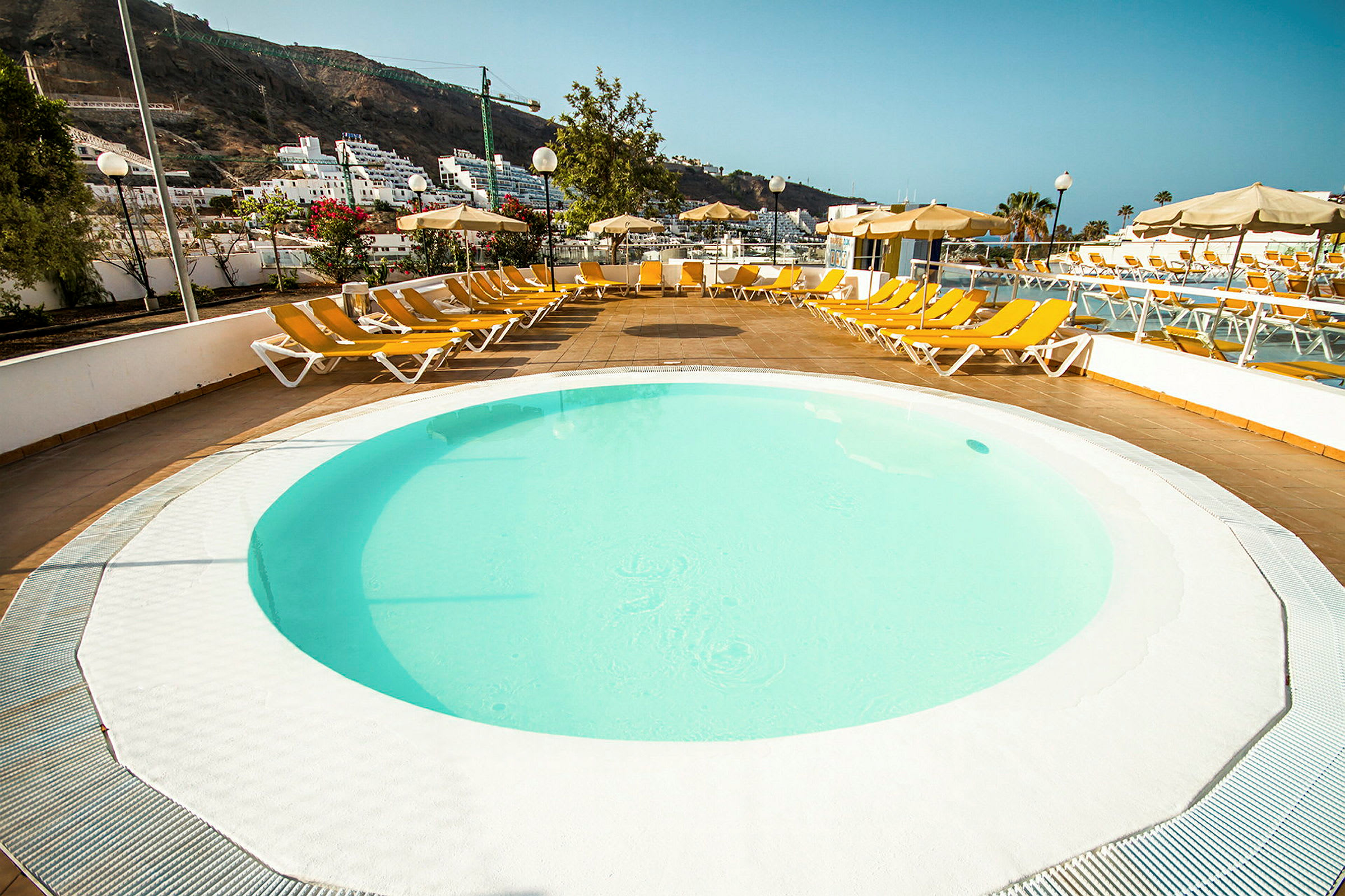 Rund pool med solstolar runtom. (AI-genererad text)