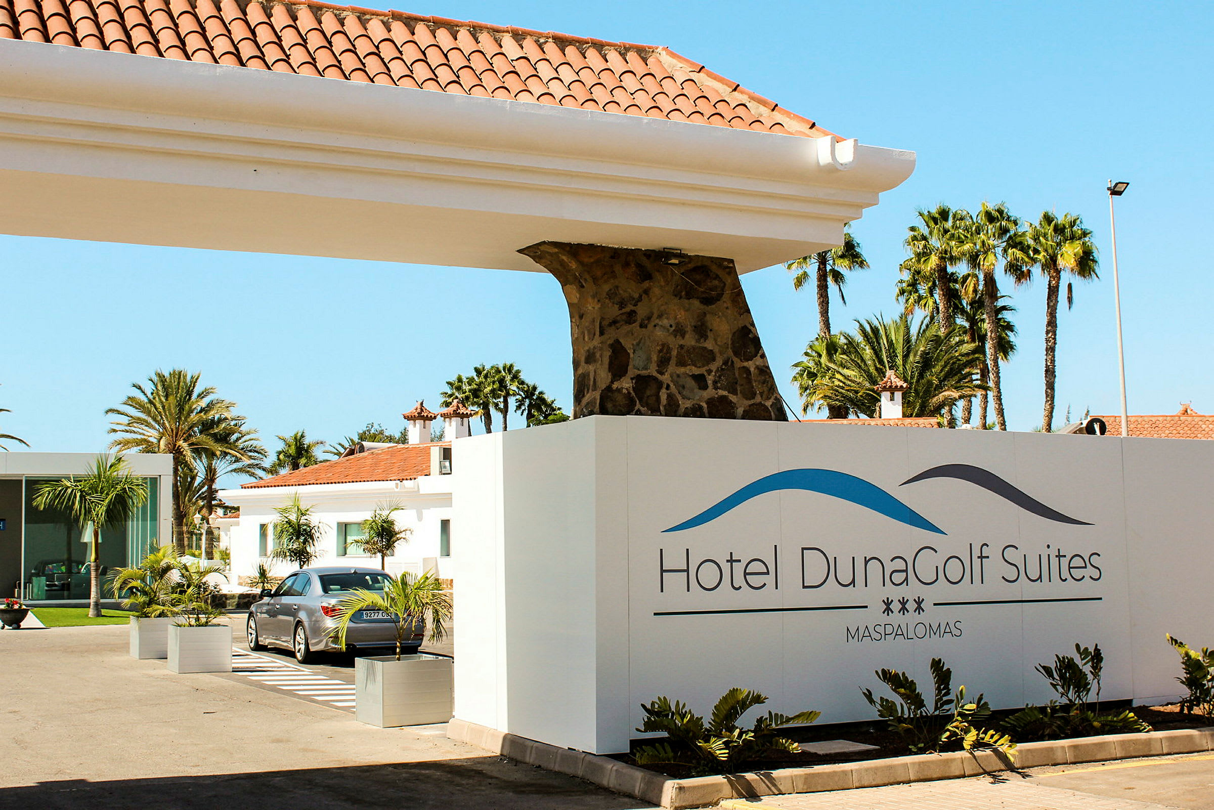 Ingången till Hotel DunaGolf Suites med skylt och byggnader i bakgrunden. (AI-genererad text)