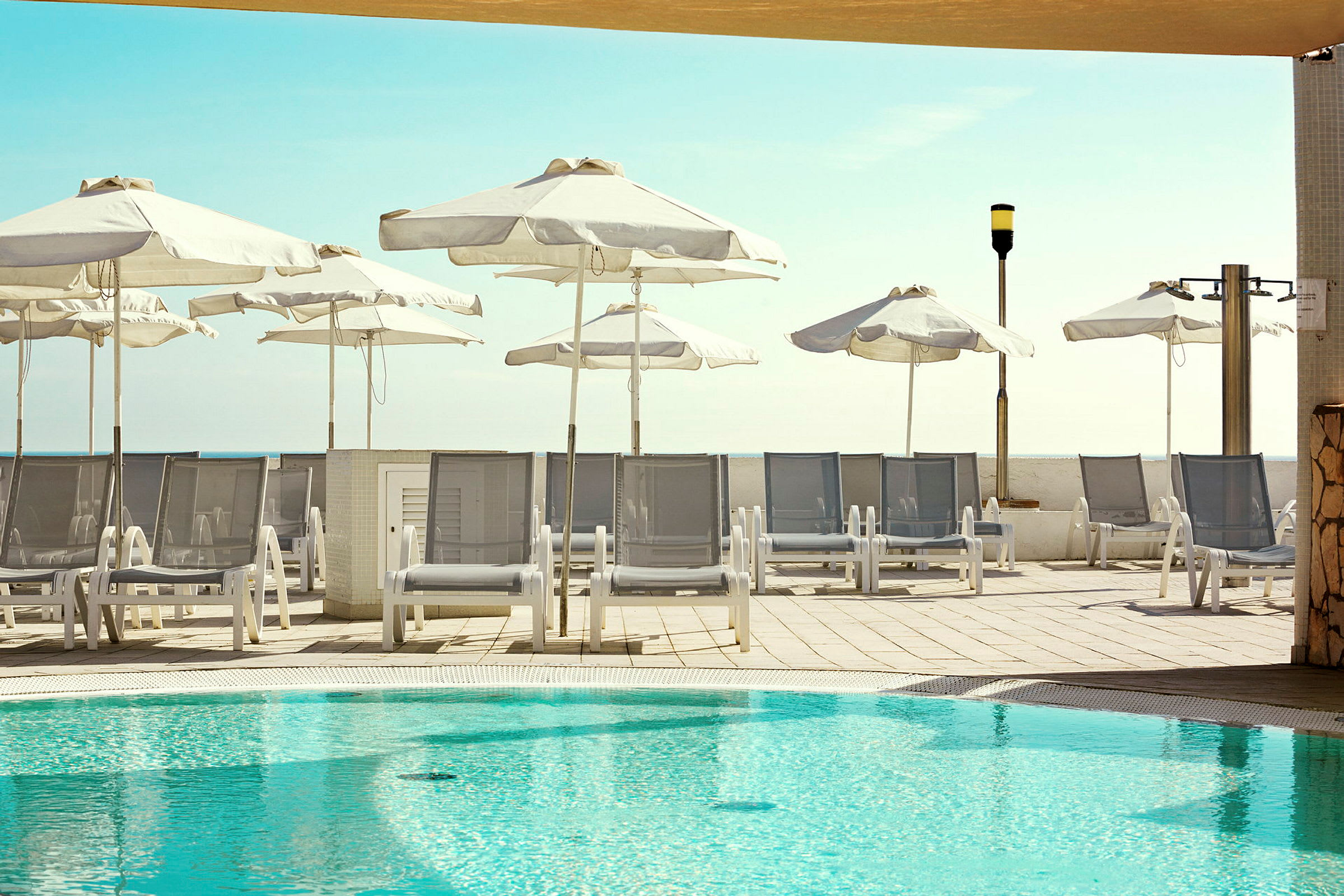 Solstolar och parasoller vid en pool. (AI-genererad text)