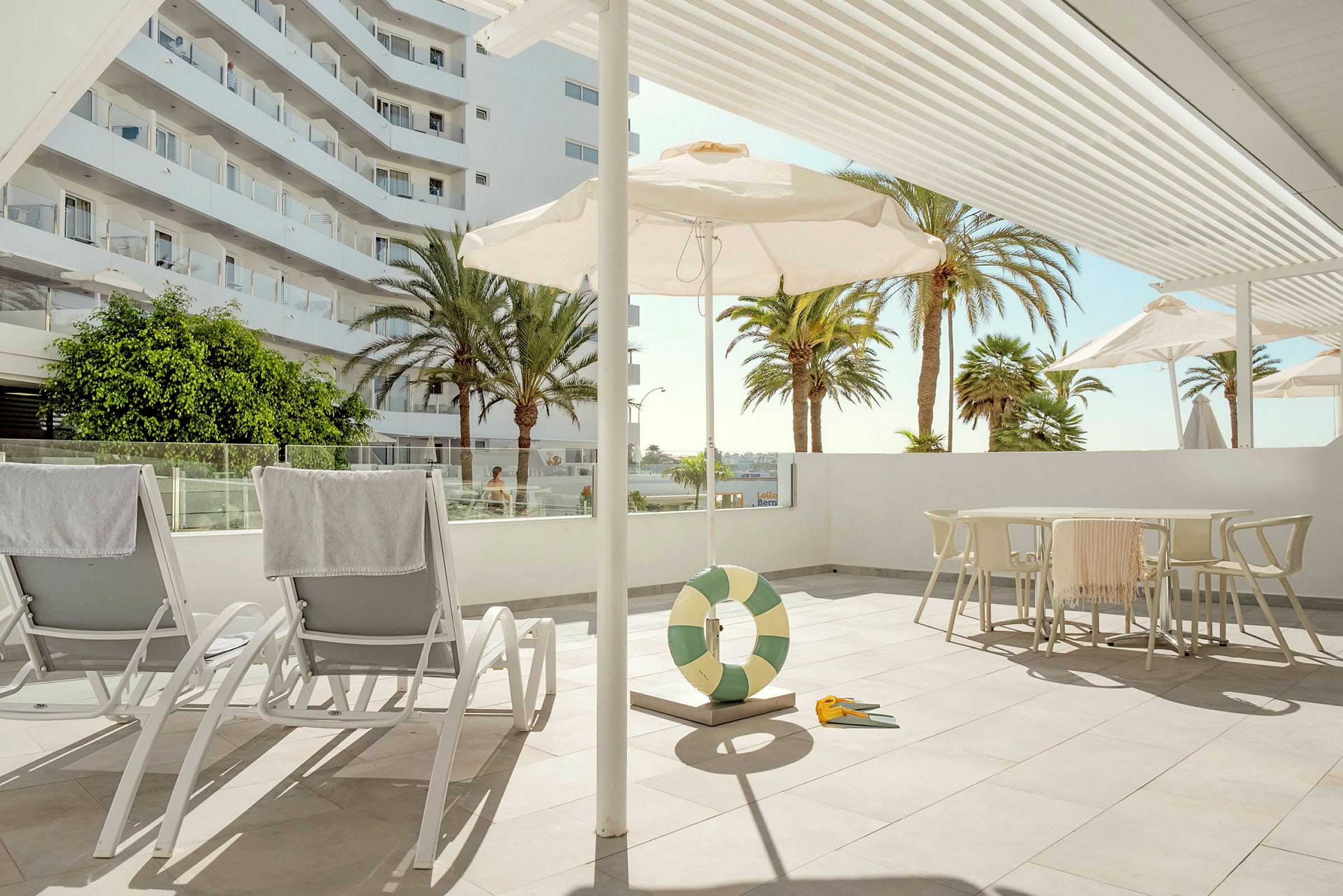 Solstolar på en solig terrass med parasoller och palmer i bakgrunden. (AI-genererad text)