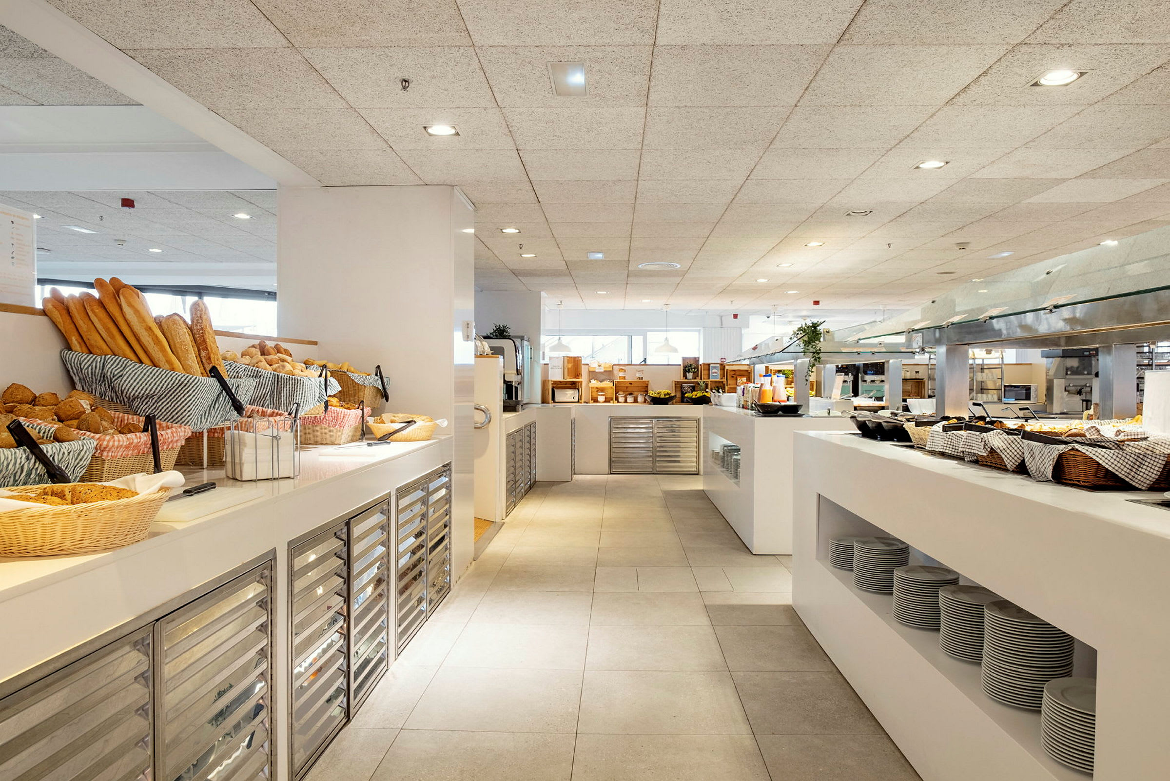 Frukostbuffé på ett hotell med nybakat bröd, tallrikar och serveringsstationer. (AI-genererad text)