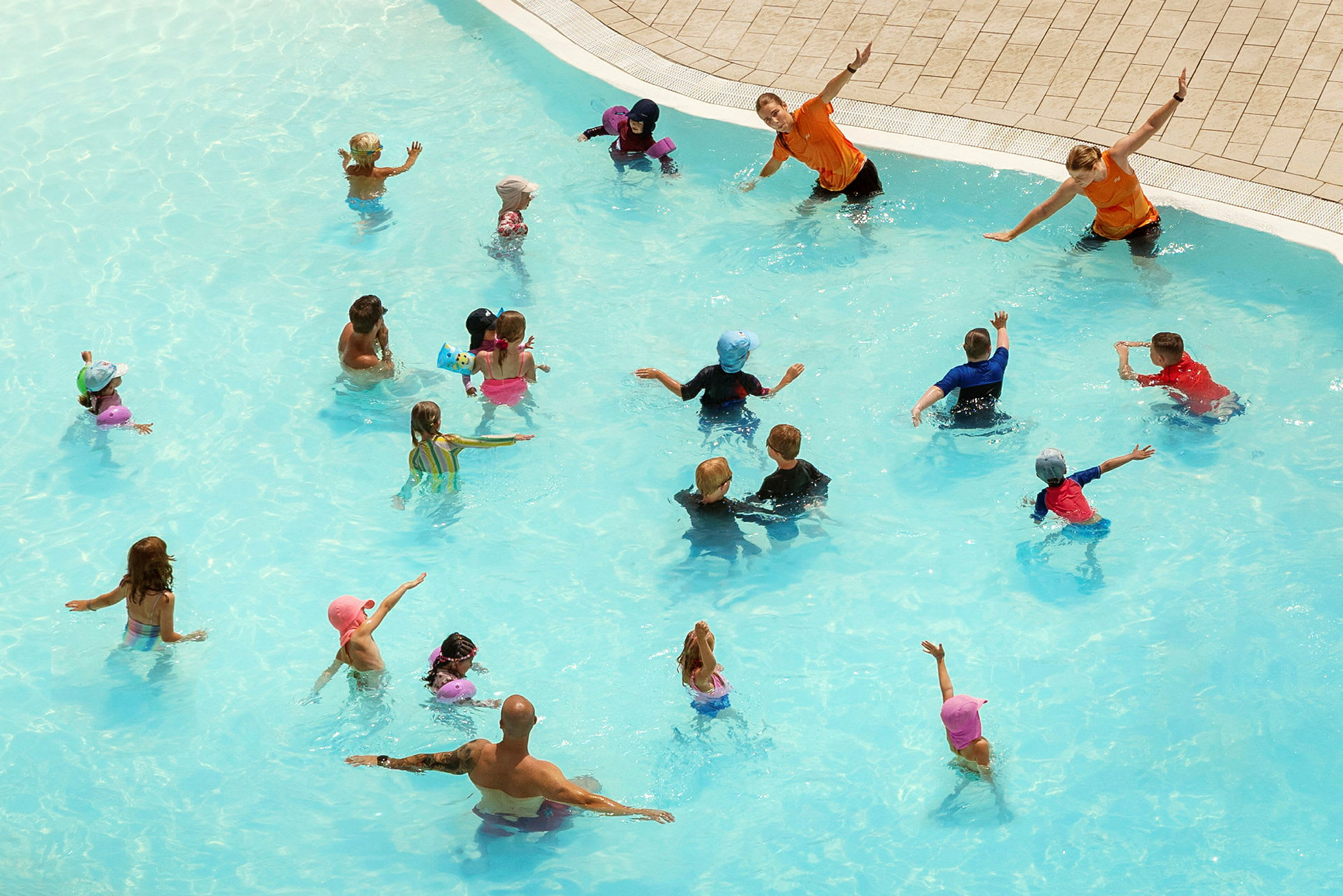 Personer leker och deltar i aktiviteter i en swimmingpool. (AI-genererad text)