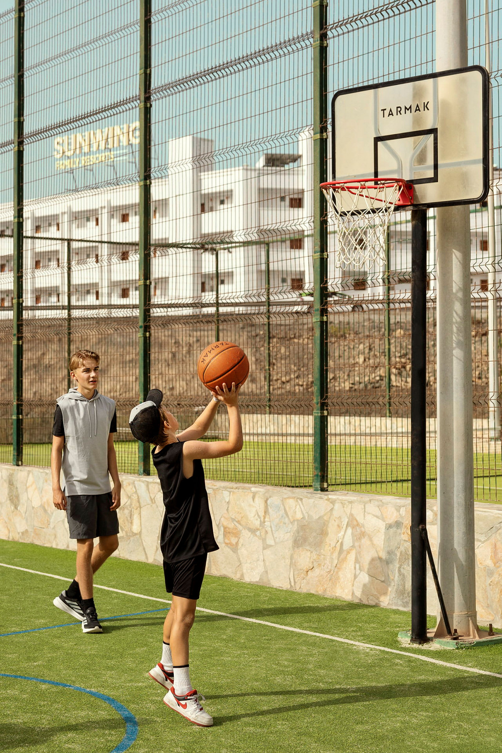 En person spelar basket utomhus mot ett nät med en boll. (AI-genererad text)