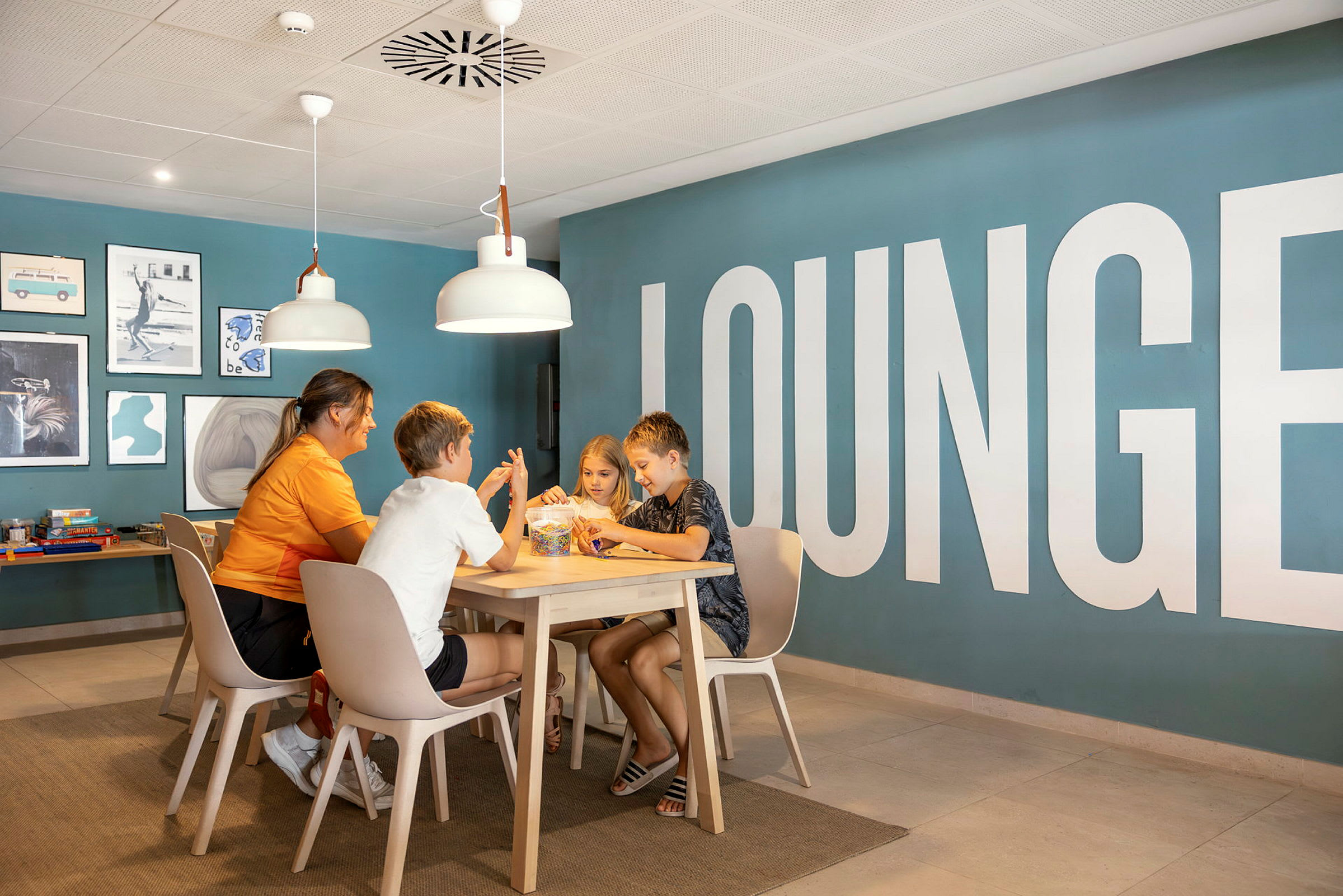 En grupp människor sitter vid ett bord i en lounge med blå väggar och dekorativ konst. (AI-genererad text)