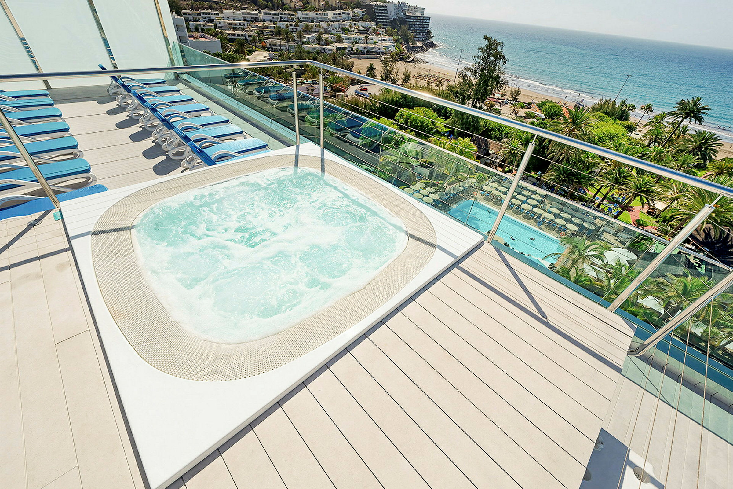 Jacuzzi och solstolar på en terrass med utsikt över havet. (AI-genererad text)