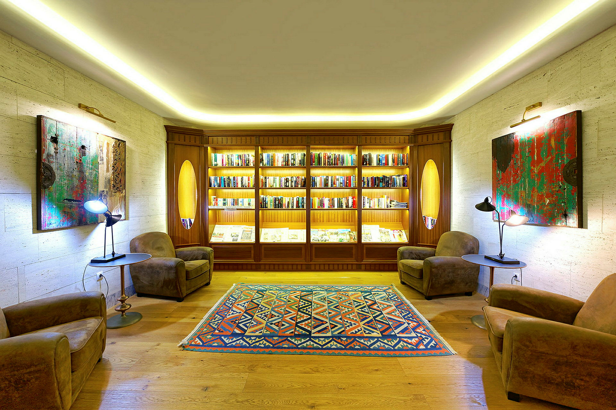 Ett välbelyst rum med bokhyllor, två fåtöljer och en färgstark matta. (AI-genererad text)