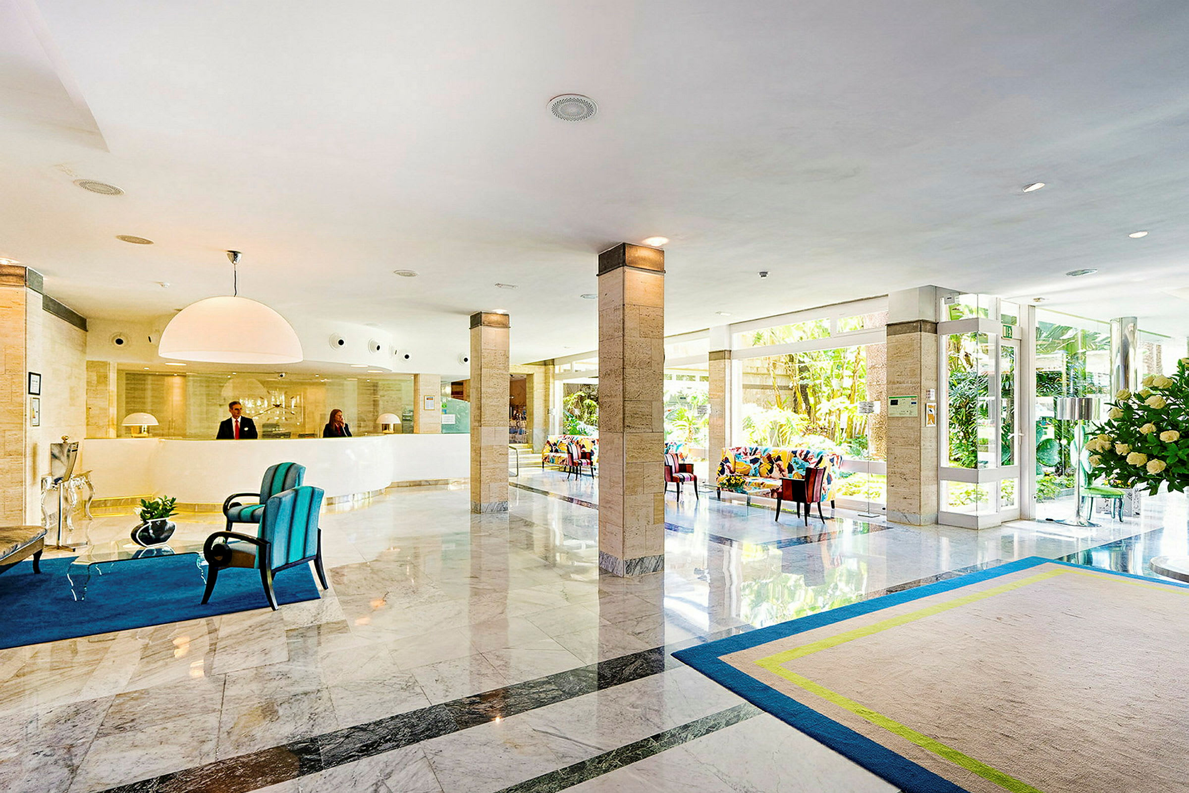 Ljus hotellobby med reception, sittmöbler och glasdörrar. (AI-genererad text)
