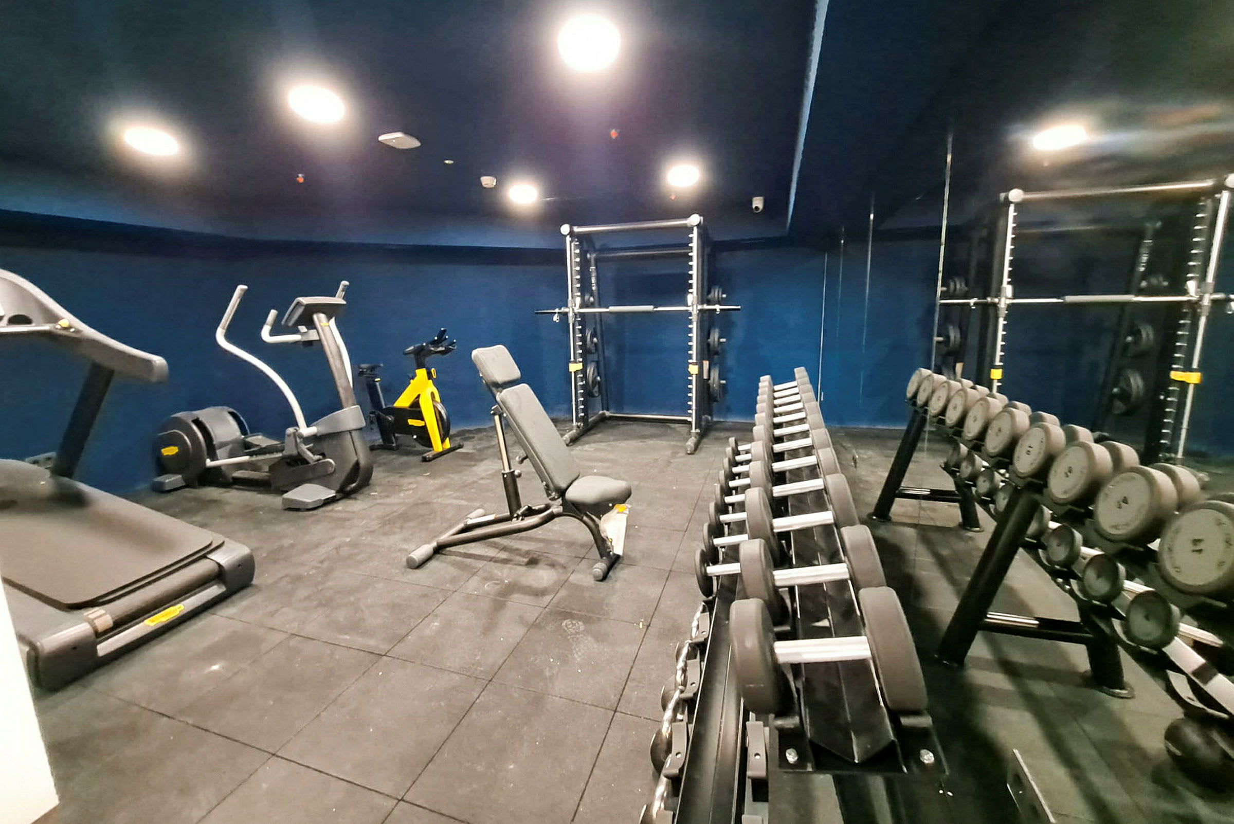 Fitnessrum med träningsmaskiner, hantlar och vikter. (AI-genererad text)