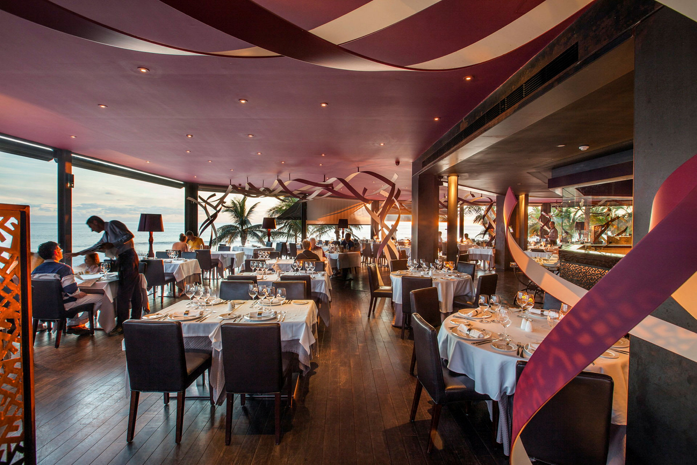 En elegant restaurang med dukade bord och havsutsikt. (AI-genererad text)