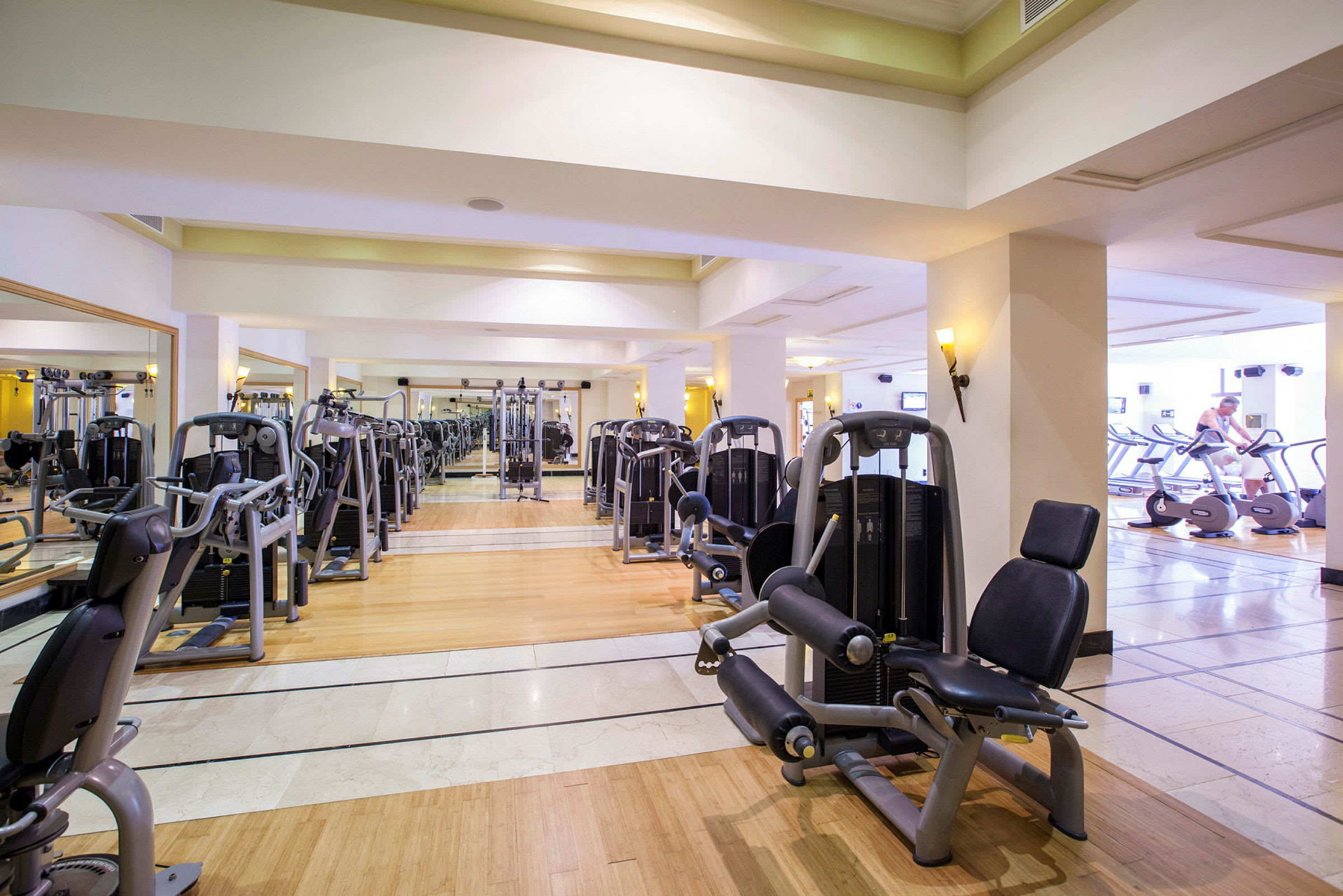 Bild av ett gym med träningsmaskiner och speglar på väggarna. (AI-genererad text)