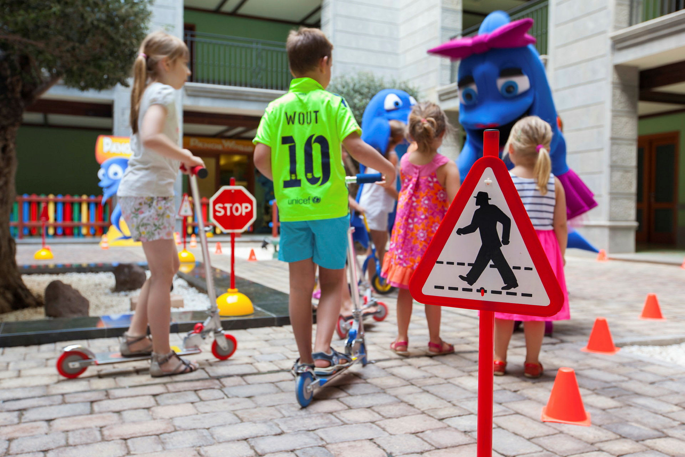 Barn leker på en bana inomhus med trafikskyltar och figurer. (AI-genererad text)