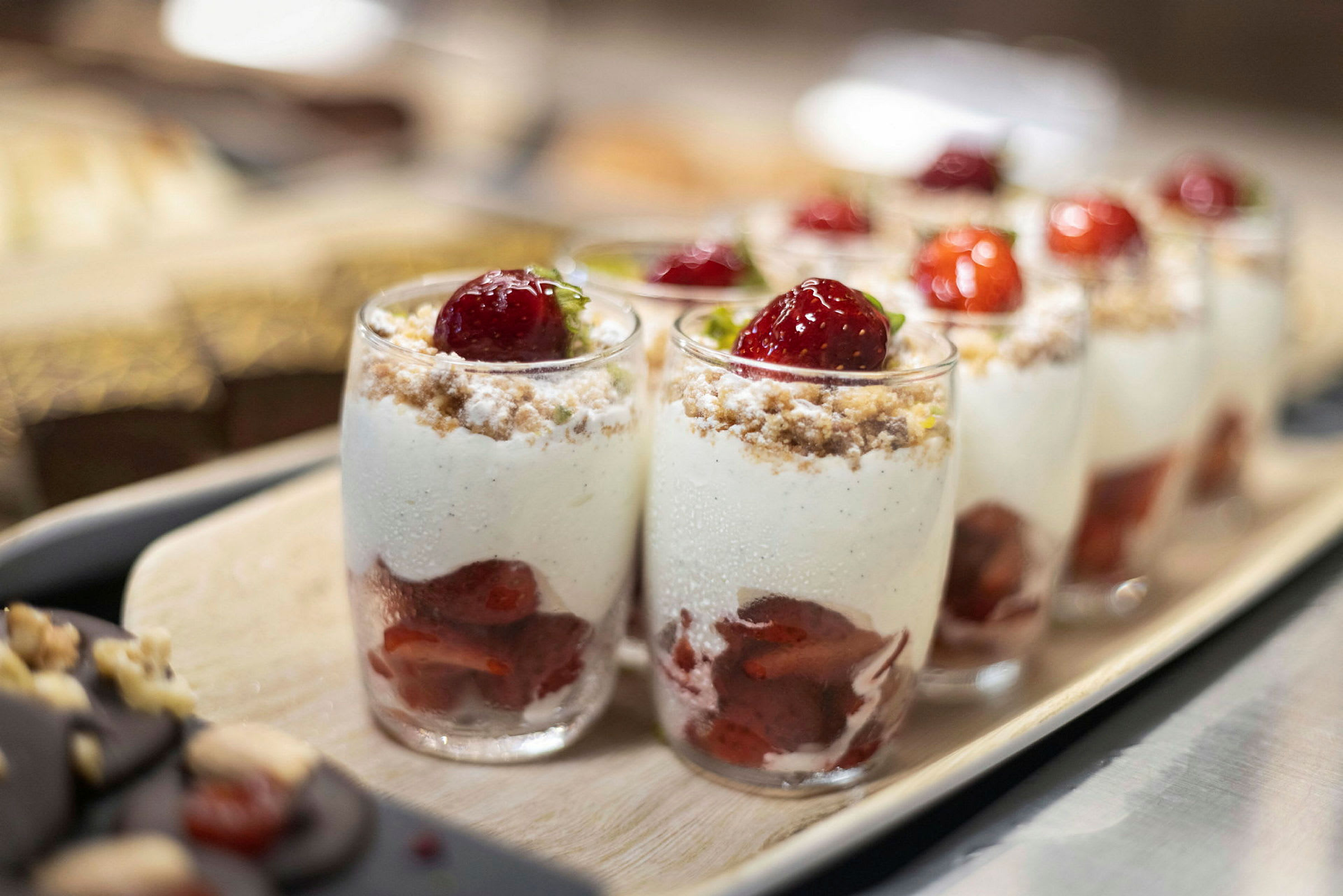 Glas med dessert bestående av jordgubbar, grädde och smulor. (AI-genererad text)