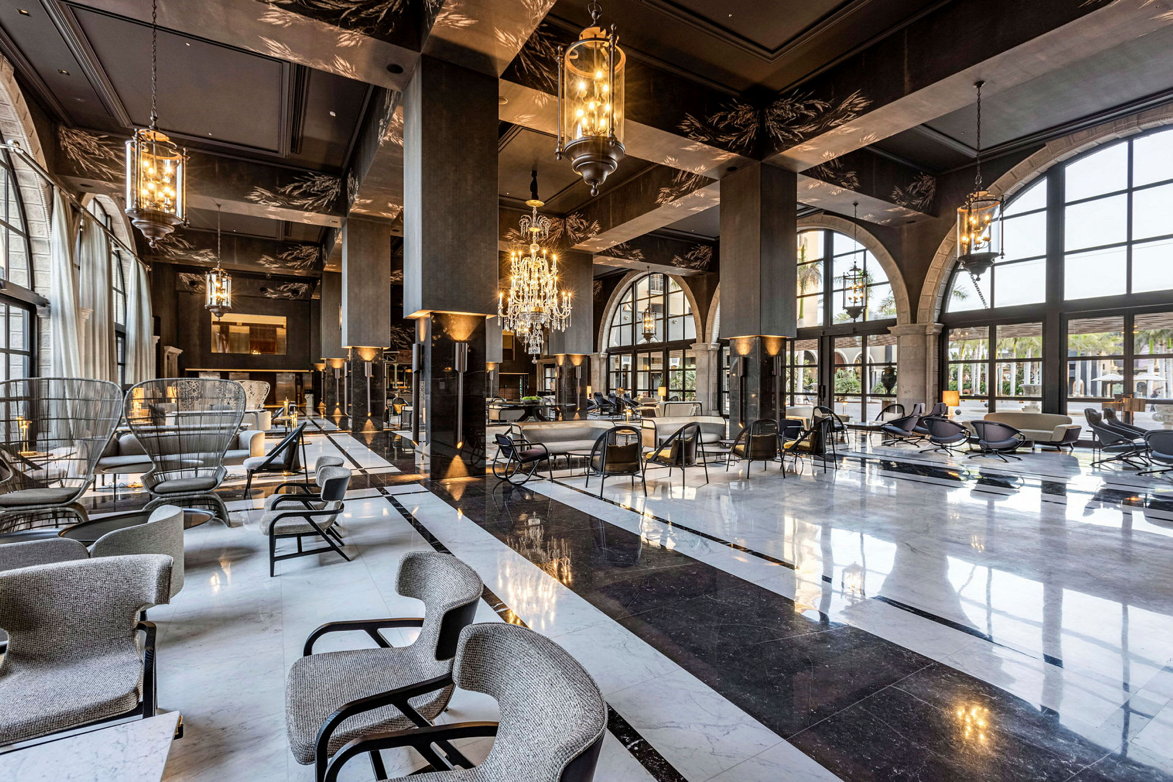 Ett stort lyxigt hotellobby med sittgrupper, en blank marmorgolv och eleganta ljuskronor. (AI-genererad text)