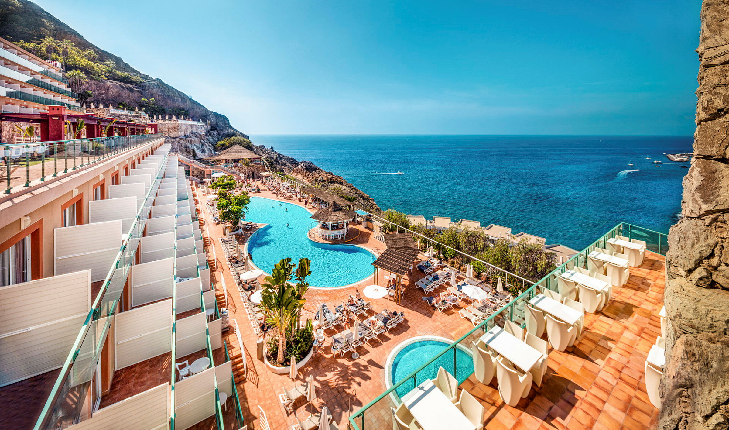 Utsikt över hotellområde med pooler och hav. (AI-genererad text)