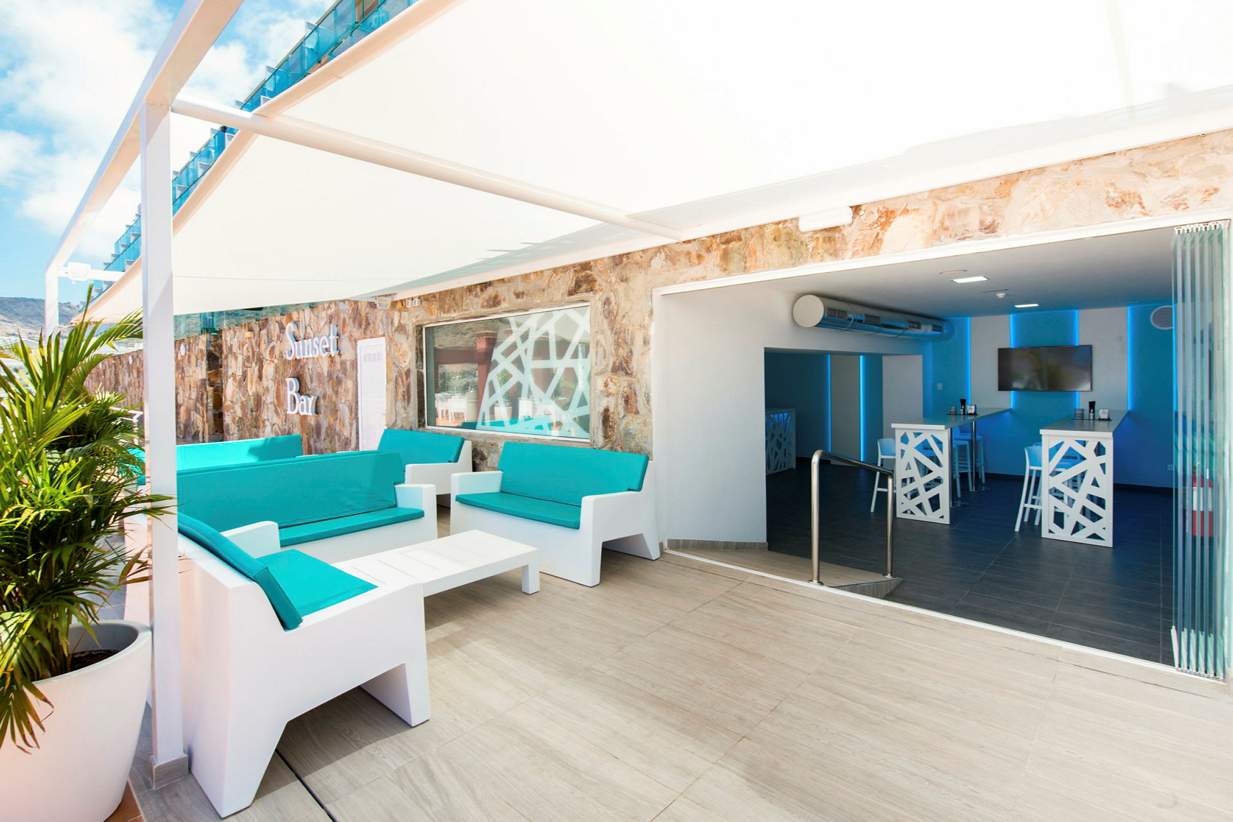 Bild av en terrass med sittgrupper och en bar med modern inredning. (AI-genererad text)