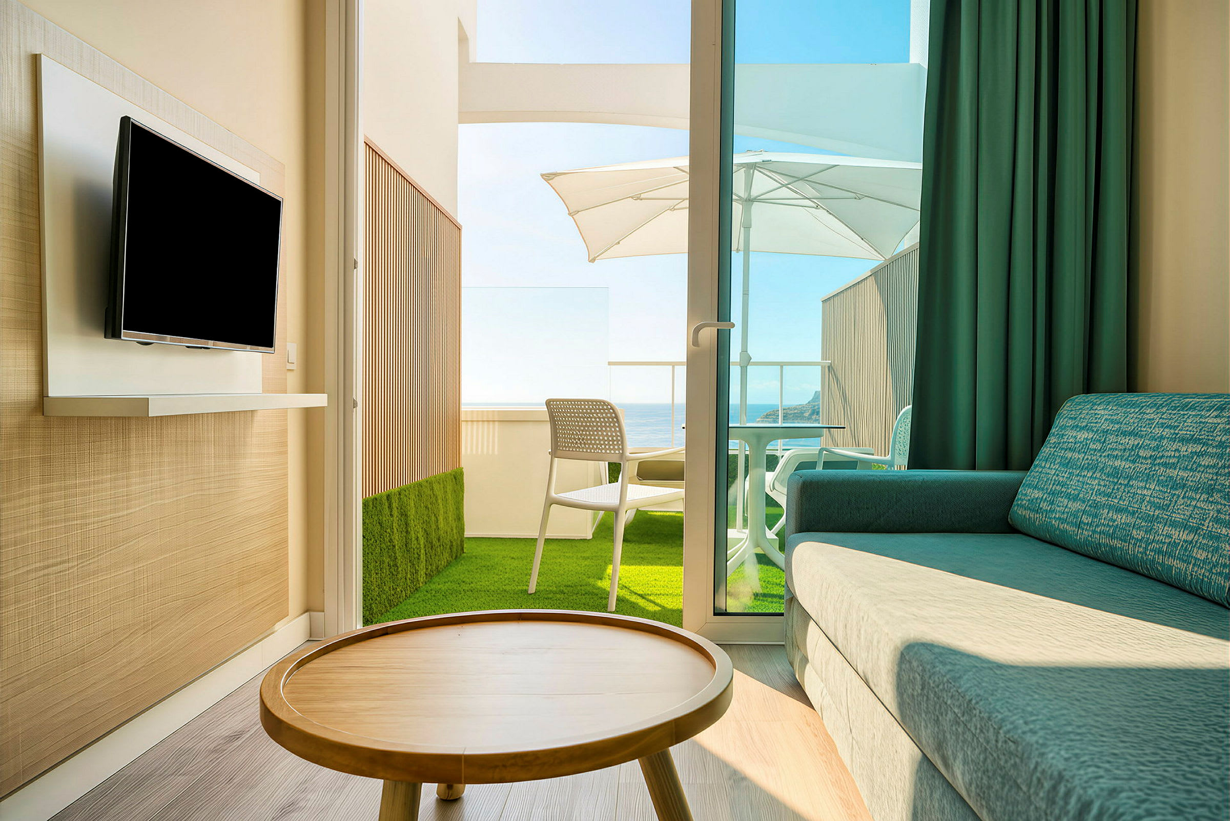 Ett hotellrum med en soffa, TV, ett träbord och en balkong med utsikt och parasoll. (AI-genererad text)