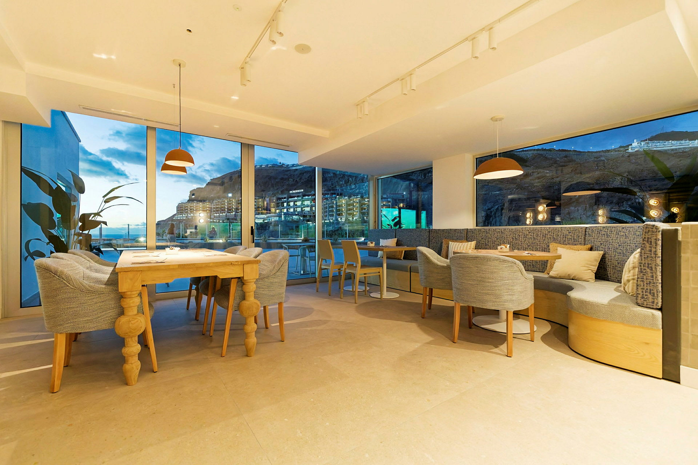 Bild på en modern restaurang med stora fönster och utsikt över kvällslandskapet. (AI-genererad text)