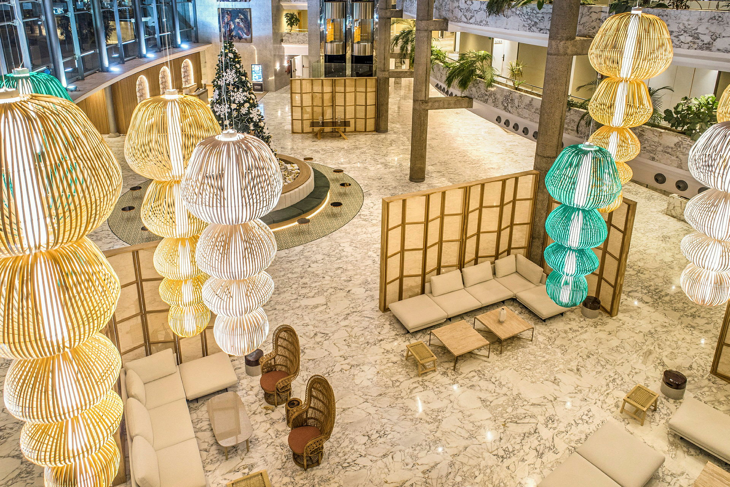 Ett hotellobby med stora, hängande belysningar och sittplatser. (AI-genererad text)